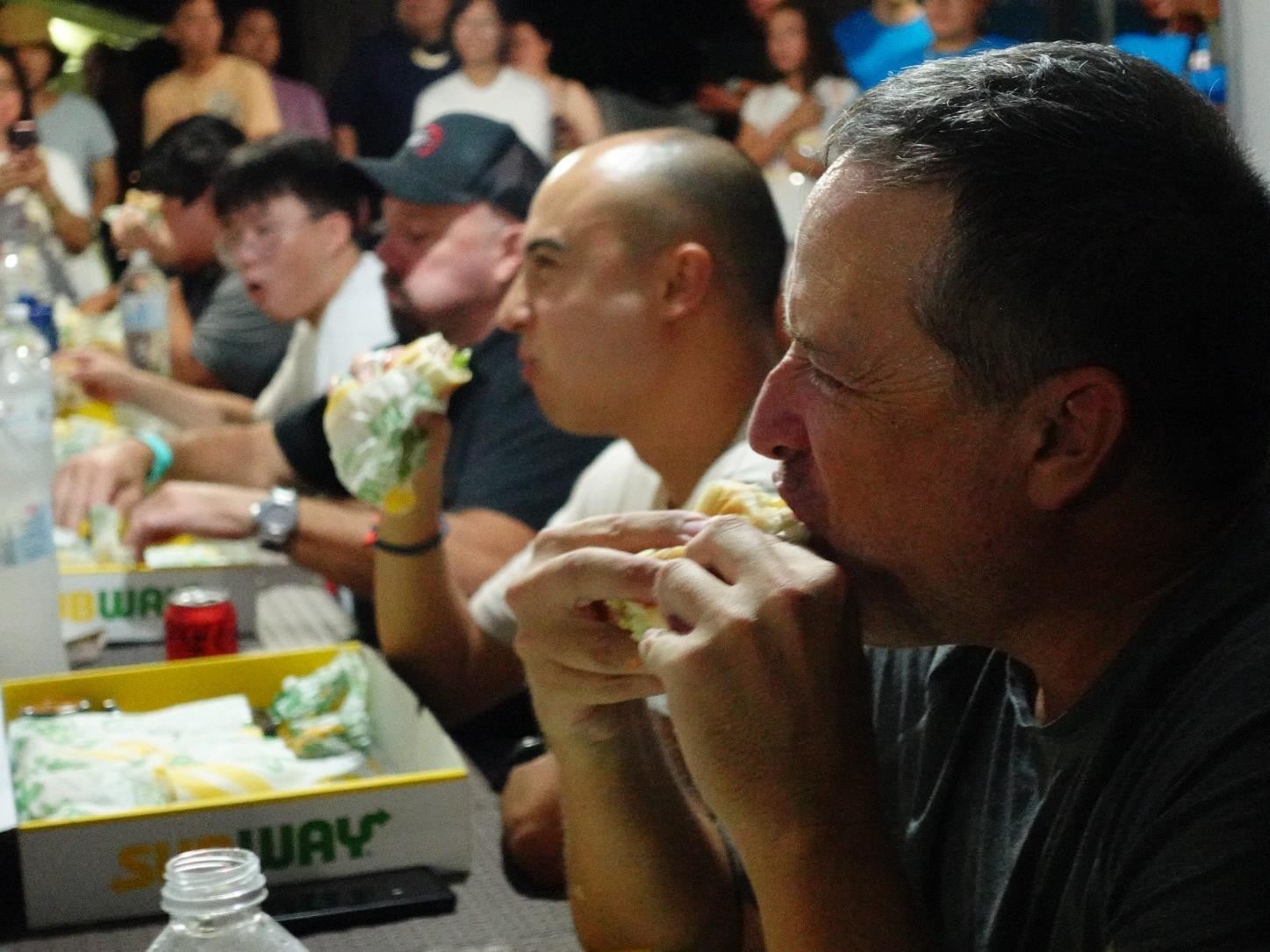 Mark McDonald and other contestants tackle five footlongs during the Subway Sandwich Challenge at the 25th Annual Taste of the Marianas International Food Festival on May 4, 2024 at American Memorial Park.