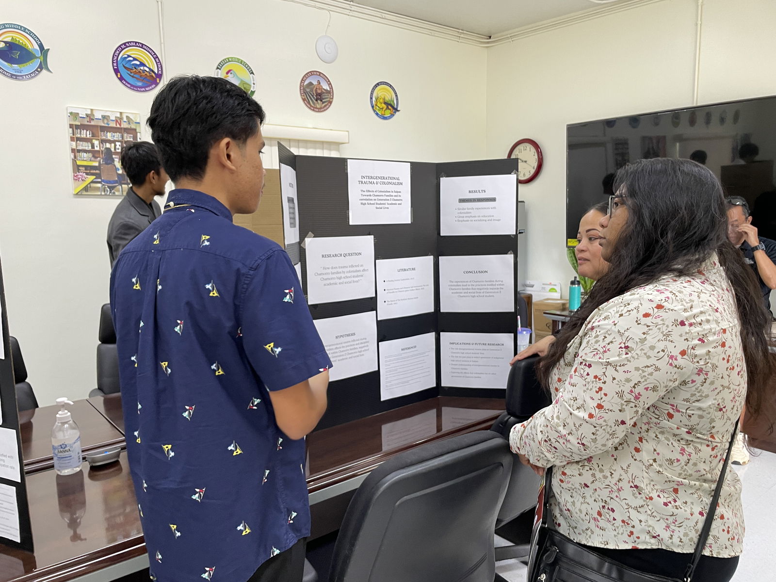 SSHS AP student Christopher Mauricio talks about his research work, “How does trauma inflicted on Chamorro families by colonialism affects Chamorro high school students’ academic and social lives” with PSS Human Resource Director Lucretia B. Deleon Guerrero and Instructional Technology and Distance Education Director Lorraine Catienza.