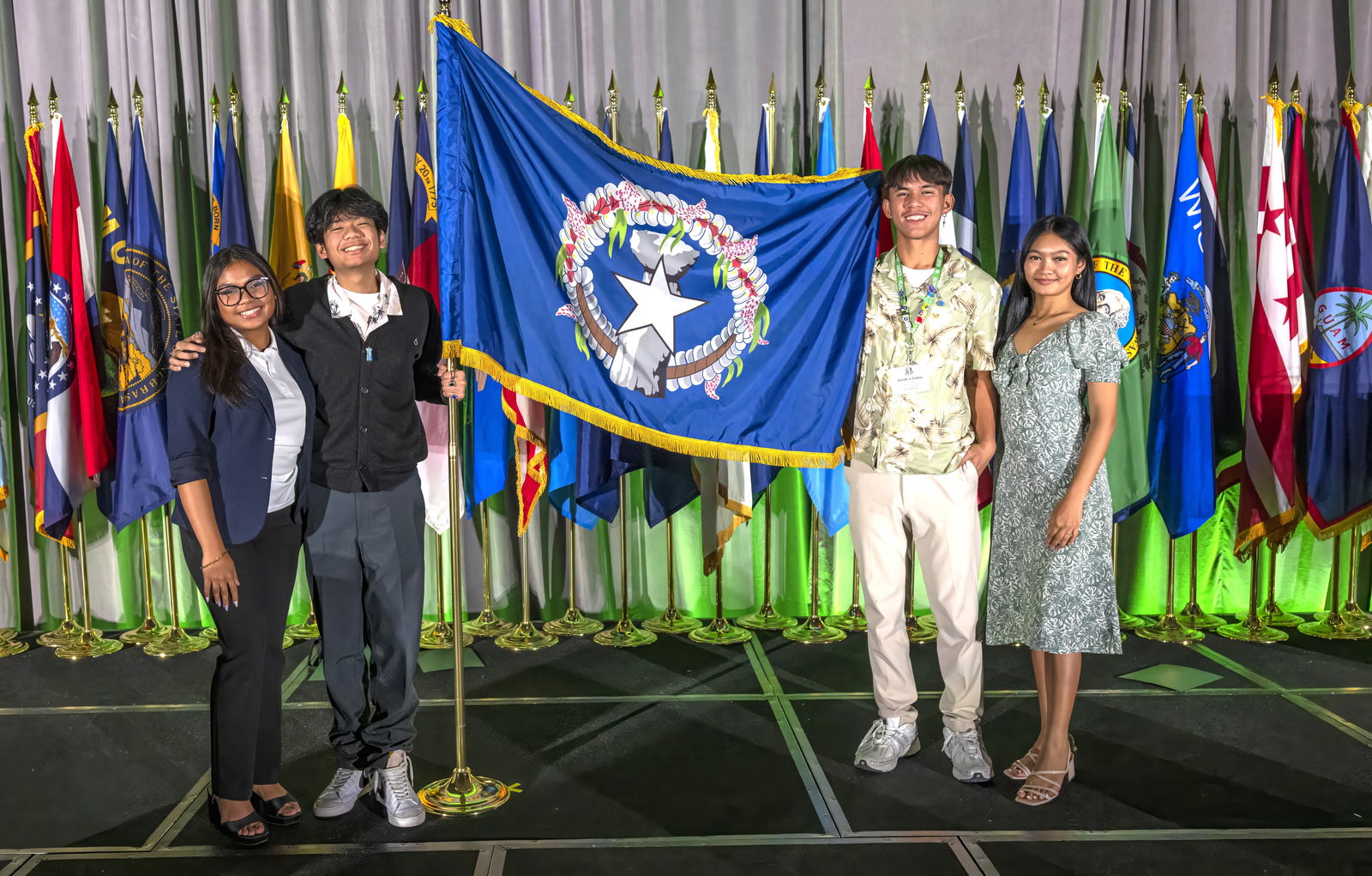 From left, Jane Mozunder, Jedric Aniciete, Joseph Santos Jr. and Clarize Rodriguez pose for a photo with the CNMI flag.