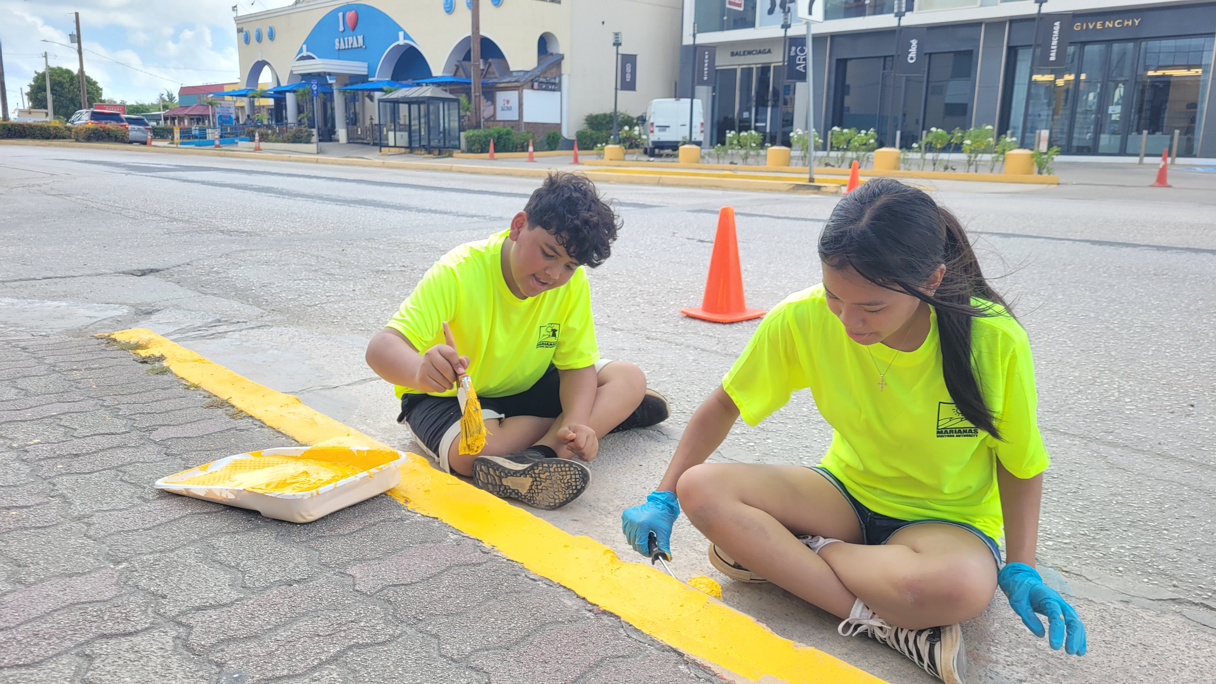 From left, MY WAVE Club member Hudson Igisomar and club secretary Charmylle Reyes of Dandan Middle School participate in the Marianas Tourism Month cleanup on May 18, 2024 by painting curbs in downtown Garapan, Saipan.
