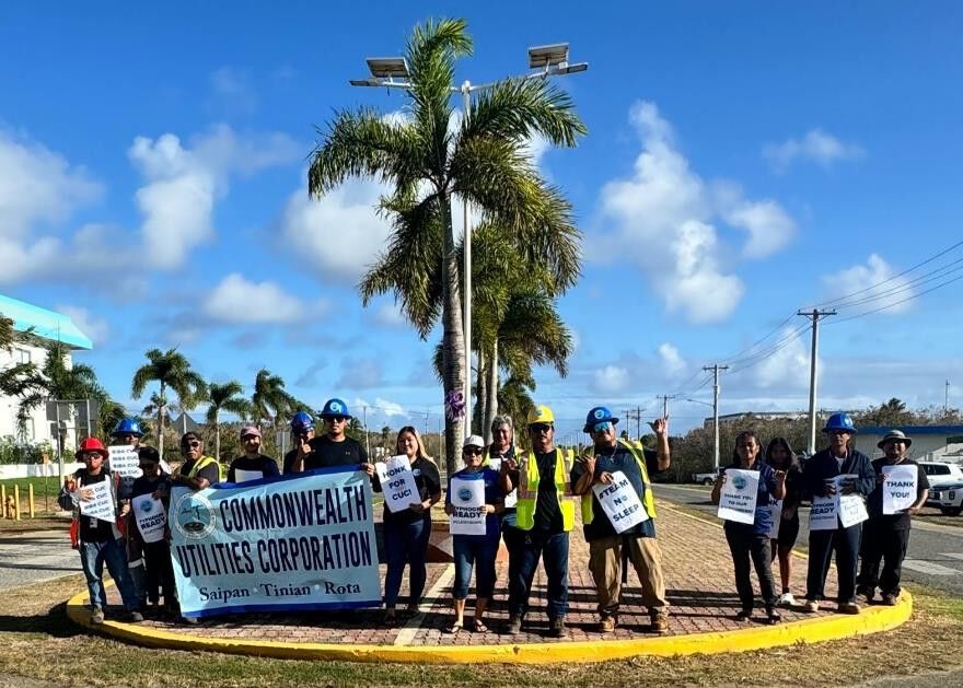 Team  spirit  shines: CUC Tinian employees come together with positivity and smiles during their roadside waving activity.