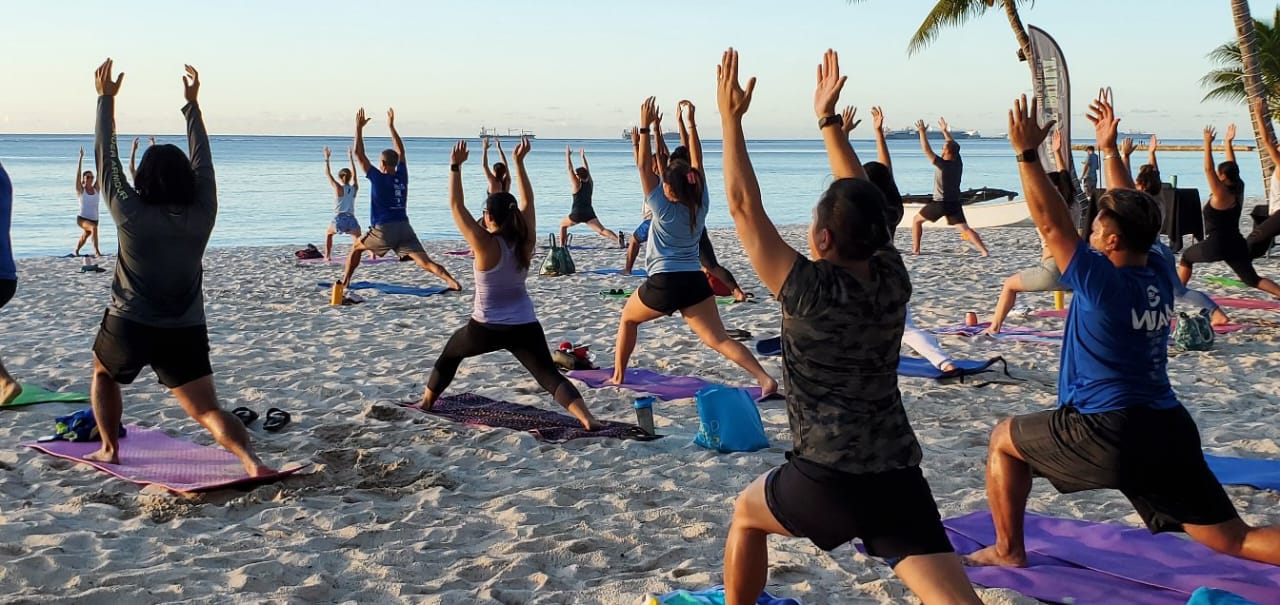 Community members take part in a yoga class offered by Latte Built Fitness at Surf Club beach.
