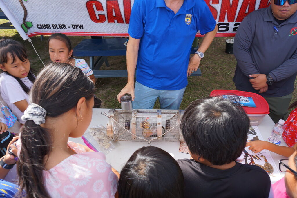 Garapan Elementary School students gather around a brown tree snake trap during a science expo on Thursday, May 23.