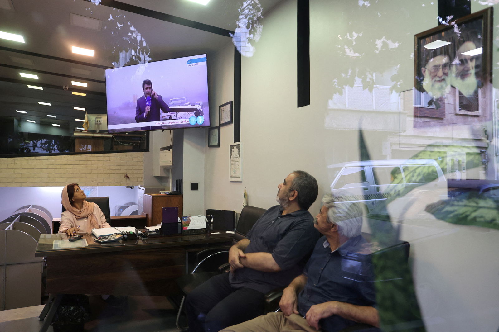 People follow the news of a crash of a helicopter carrying Iran's President Ebrahim Raisi, on a TV in a shop in Tehran, Iran, May 19, 2024.