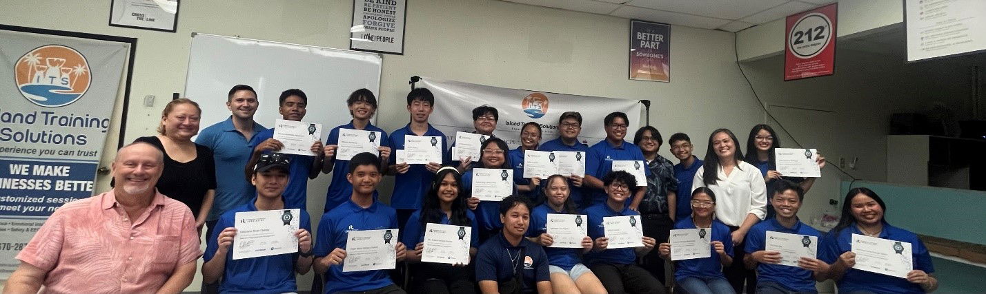 Jim Arenovski of Island Training Solutions, seated, with Dr. Jessica Taylor, Career Technical Education head, far left, and Bel Busby, right standing in white, IT instructor for Island Training Solutions, Dan Montano, assistant instructor, kneeling center, Trey Hocog, ITS marketing assistant, with MHS IT specialists. 