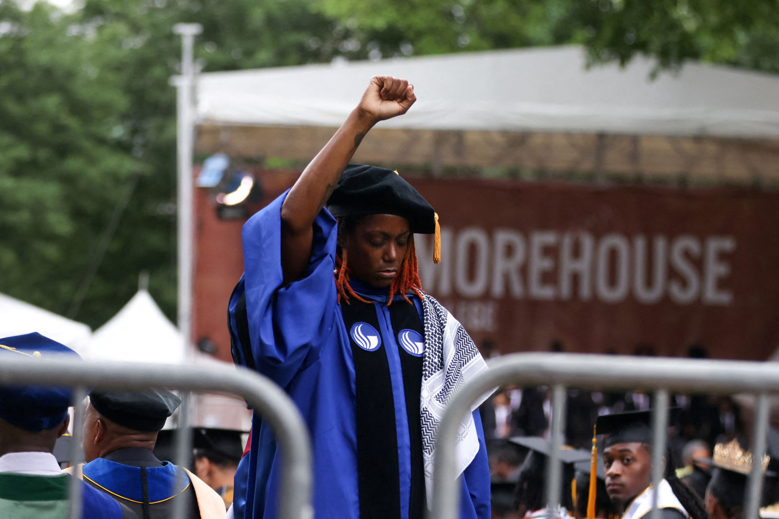 A woman stands with her back turned and holding up her fist during a speech by President Joe Biden at the Morehouse College commencement ceremony in Atlanta, Georgia, May 19, 2024.