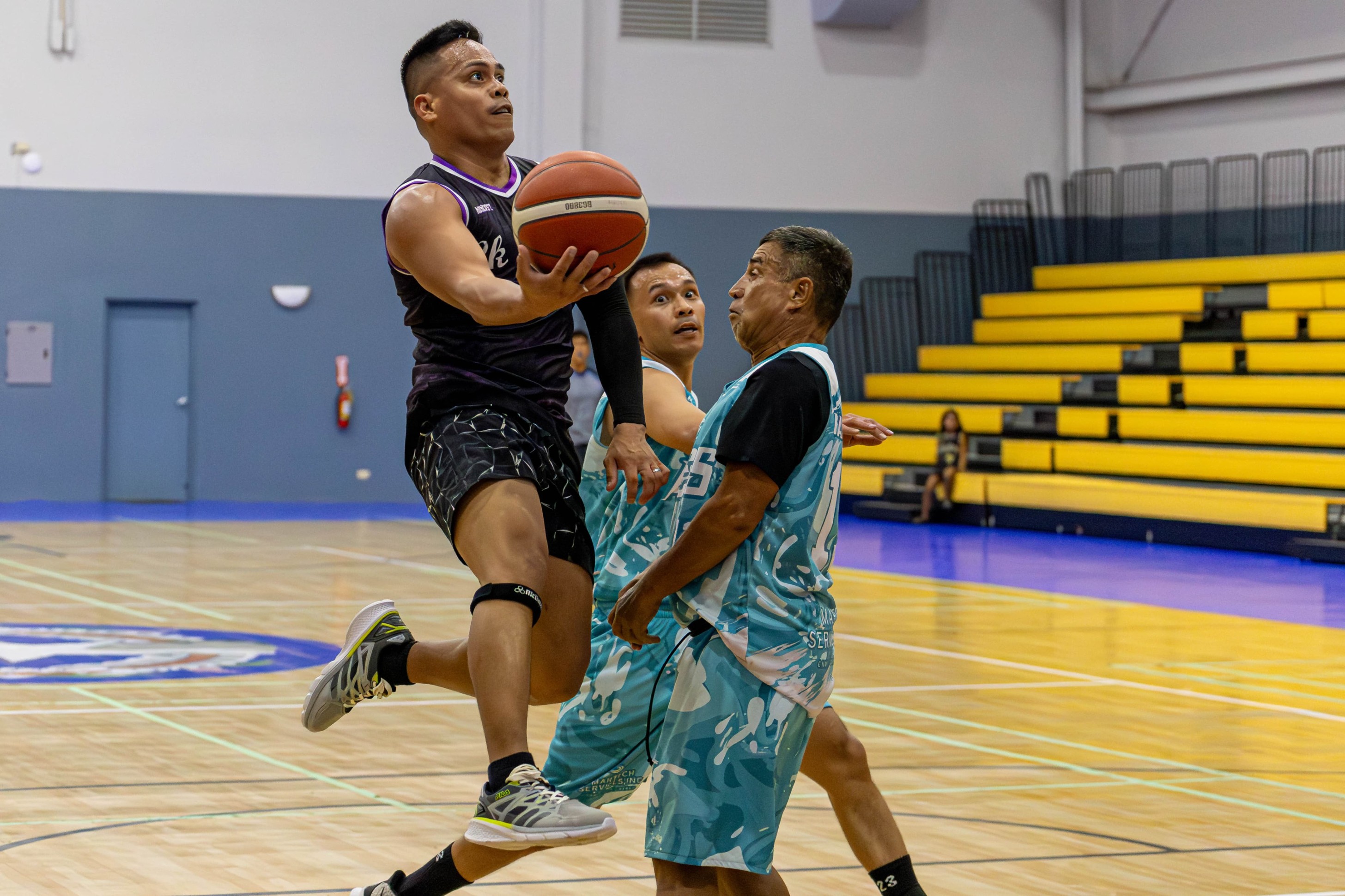 The Saints' Leo Galarse extends for the right-hand finish against two Ol'Aces defenders during a Michelob Ultra Cup 2024 game at the Ada gym on Tuesday.