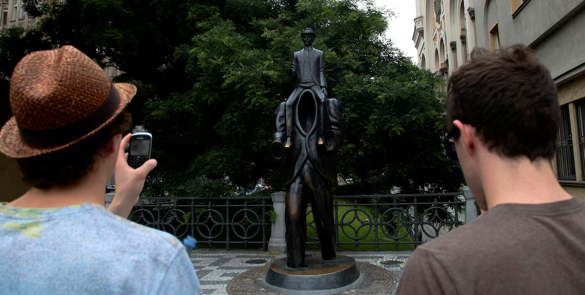Tourists look at a statue of famous German-language writer Franz Kafka in central Prague, July 3, 2013, on the day marking the 130th anniversary of his birth in Prague.