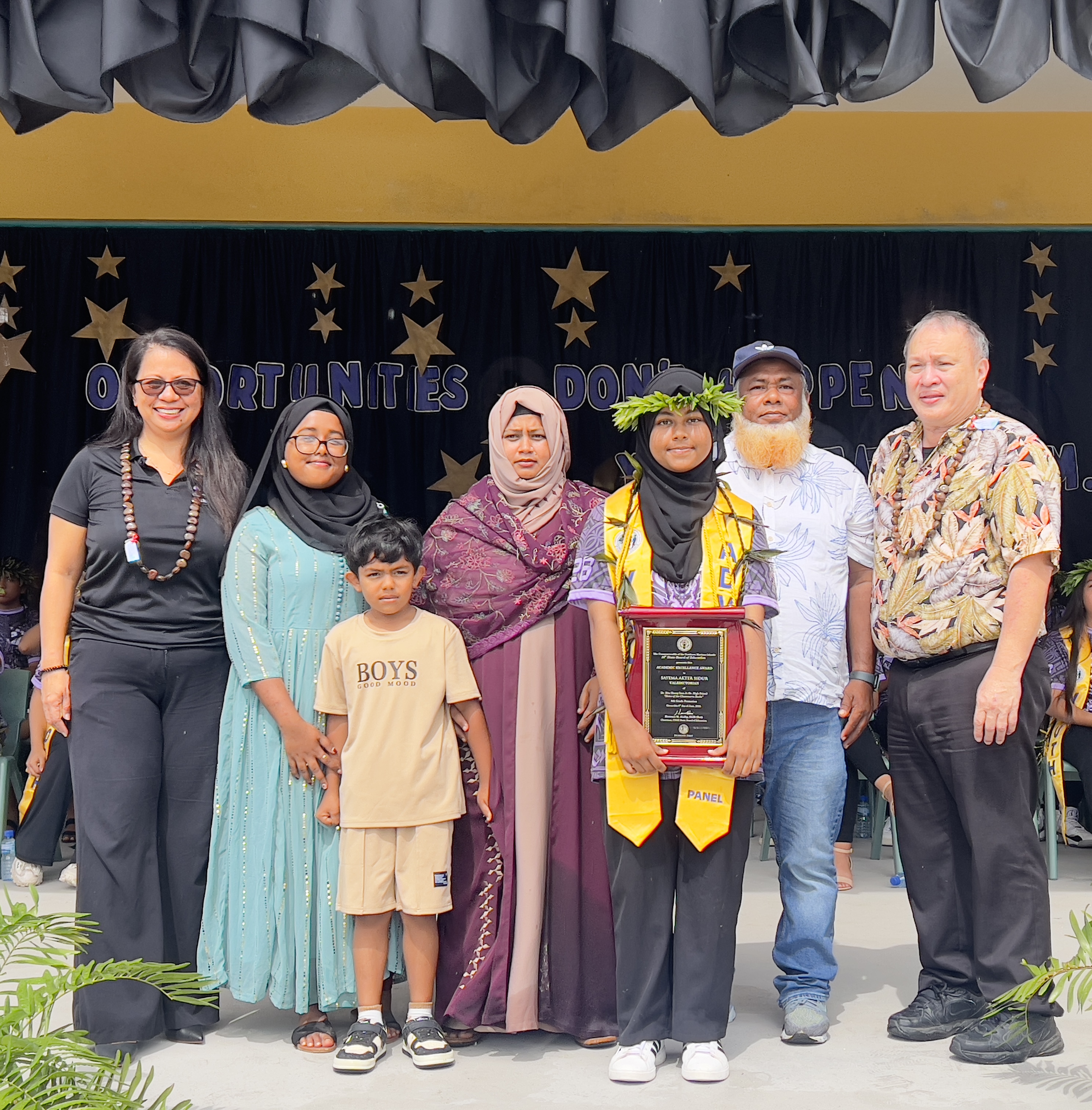 Valedictorian Sayema A. Sidur is joined by her family on stage to receive her Board of Education Academic Excellence Award from acting BOE Chair Maisie B. Tenorio and member Andrew L. Orsini.