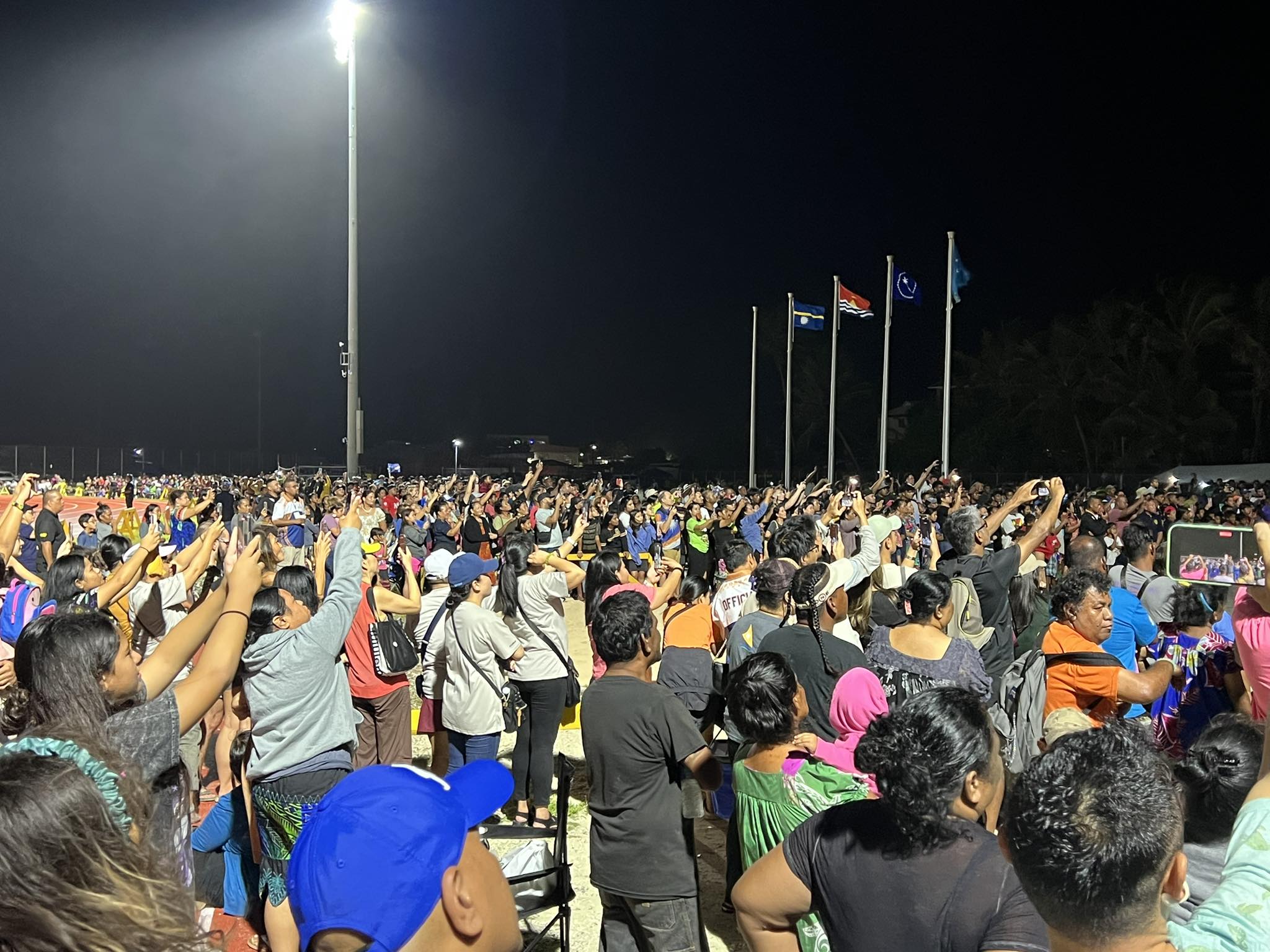 Thousands crowded into the track field for the Micronesian Games opening ceremony, focusing their phone cameras on the lighting of the Games flame by Marshall Islands wrestling star Waylon Muller.