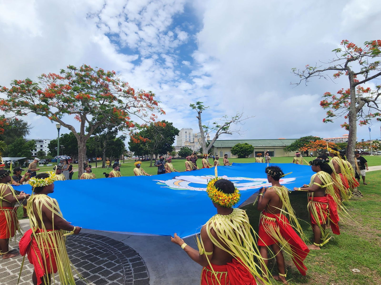 Traditional Carolinian dancers hold a big CNMI flag as they march toward the Marianas Memorial, which honors the Chamorro and Carolinian civilians who perished during the Battle of Saipan.