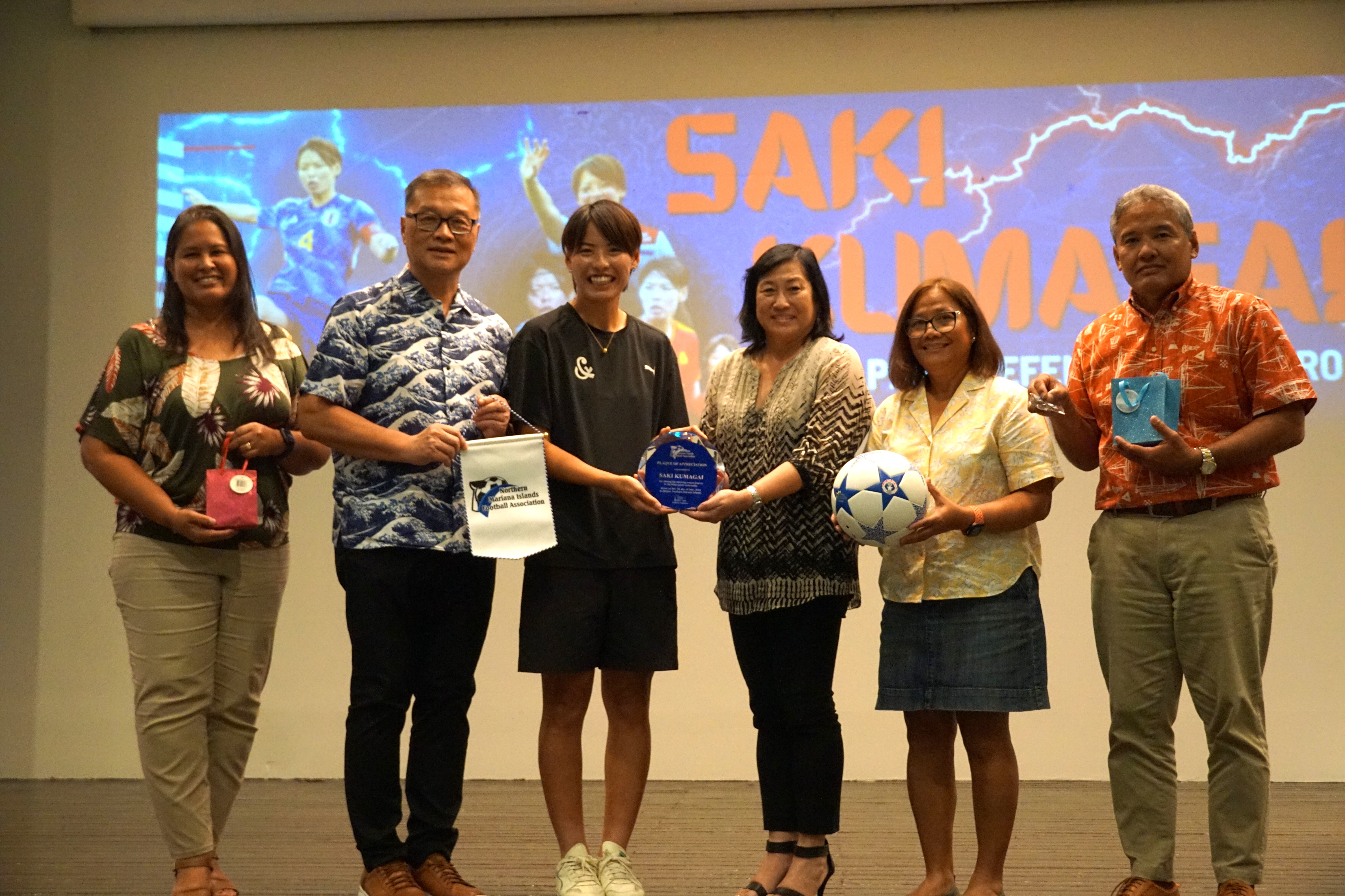 Saki Kumagai, third left, poses with NMI Football Association Executive Committee member Catherine Toves, President Jerry Tan, VP Vickie Izuka, Treasurer Elna Curate and Executive Committee member Alex Sablan at the conclusion of Kumagai’s presentation in the Hibiscus Hall of Crowne Plaza Resort Saipan on Friday.