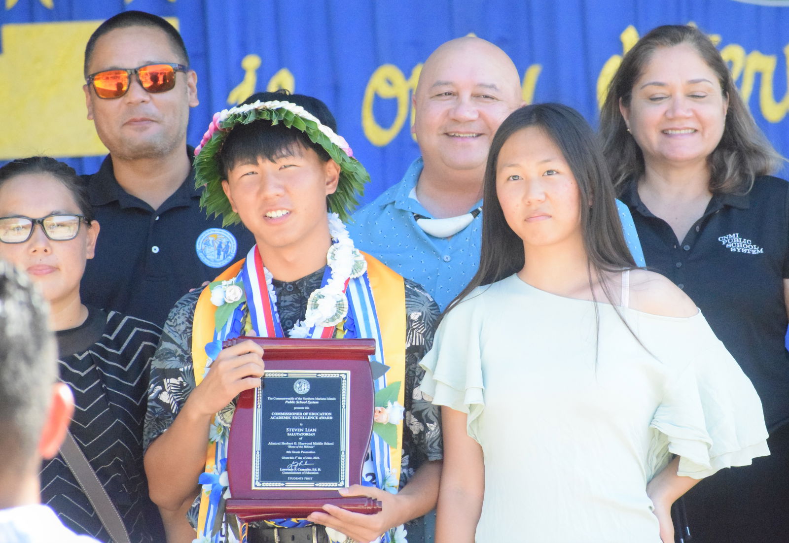 Salutatorian Steven Lian holds his award as he poses for a photo with  Commissioner of Education Dr. Lawrence F. Camacho, Special Education Director Donna Flores, right, and Lian’s family.