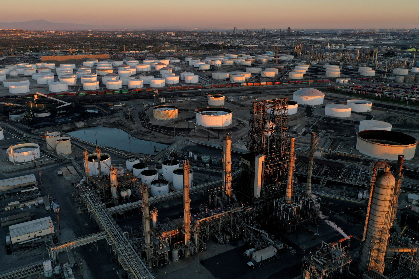 A view of the Phillips 66 Company's Los Angeles Refinery, foreground, which processes domestic and imported crude oil into gasoline, aviation and diesel fuels, and storage tanks for refined petroleum products at the Kinder Morgan Carson Terminal, background, at sunset in Carson, California, March 11, 2022.