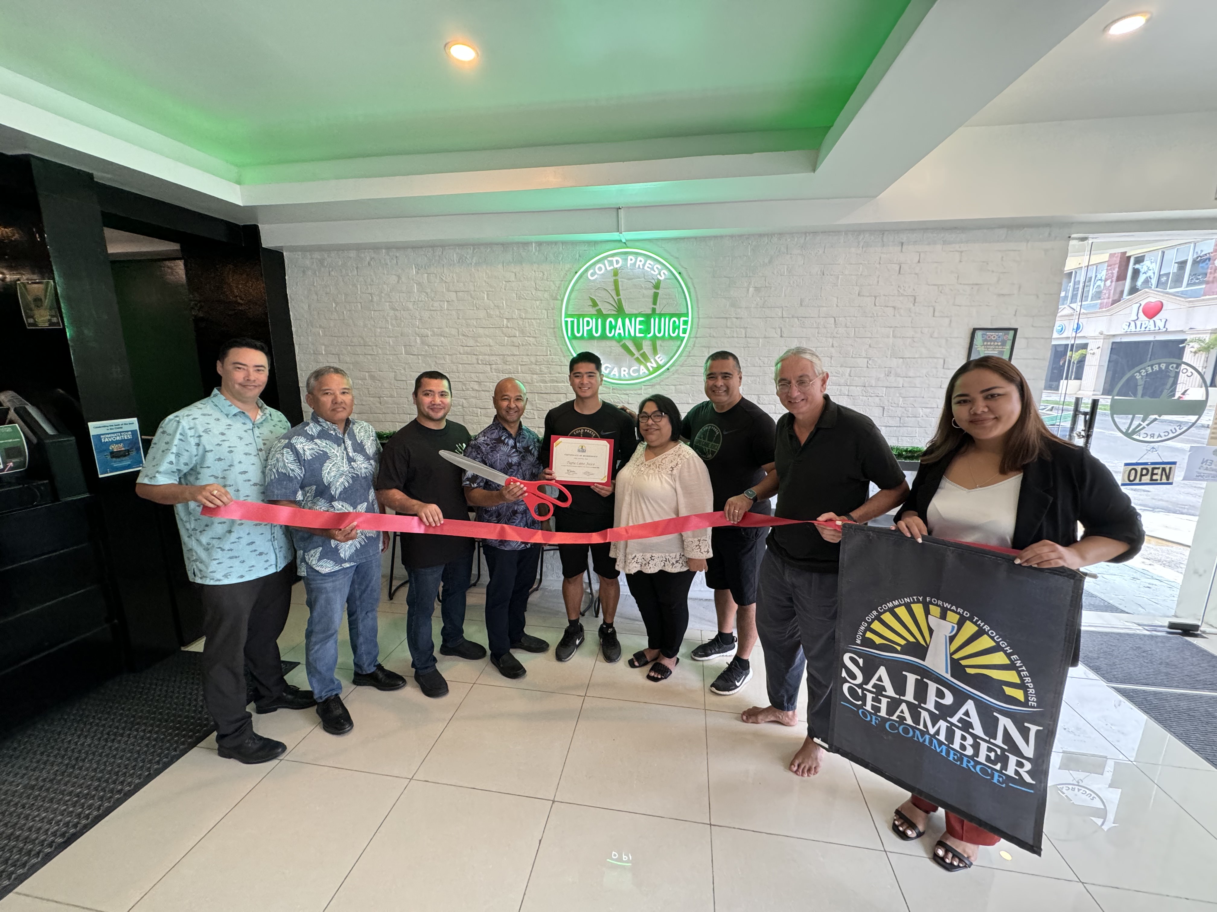 Cameron Atalig, center, owner and operator of Tupu Cane Juice, and his team join the SCC leadership in ceremonial ribbon cutting as a new chamber member.