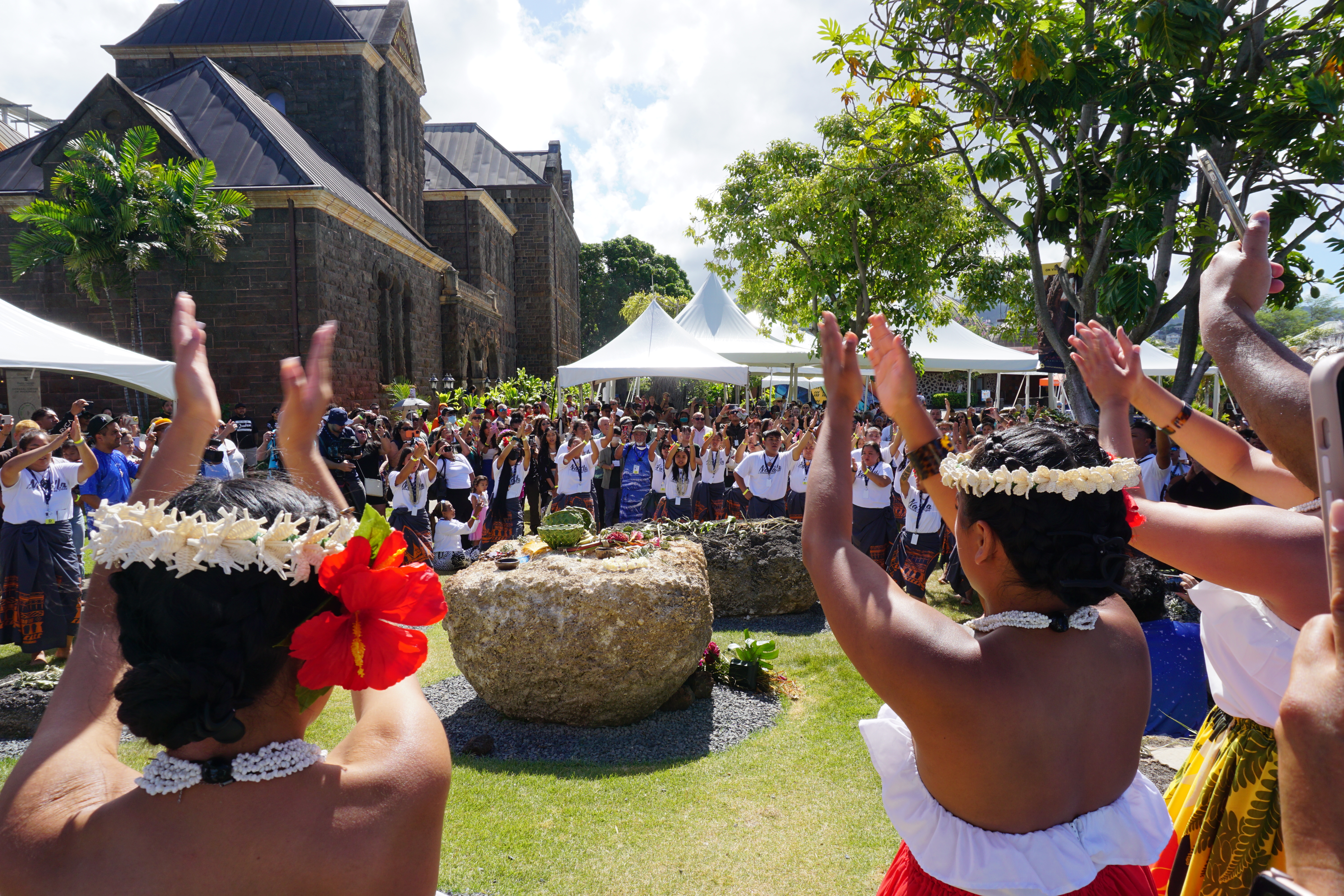 Diaspora Chamorros pictured in the foreground perform a dance in honor of three latte sets displayed at the Bishop Museum in Honolulu, Hawaii.