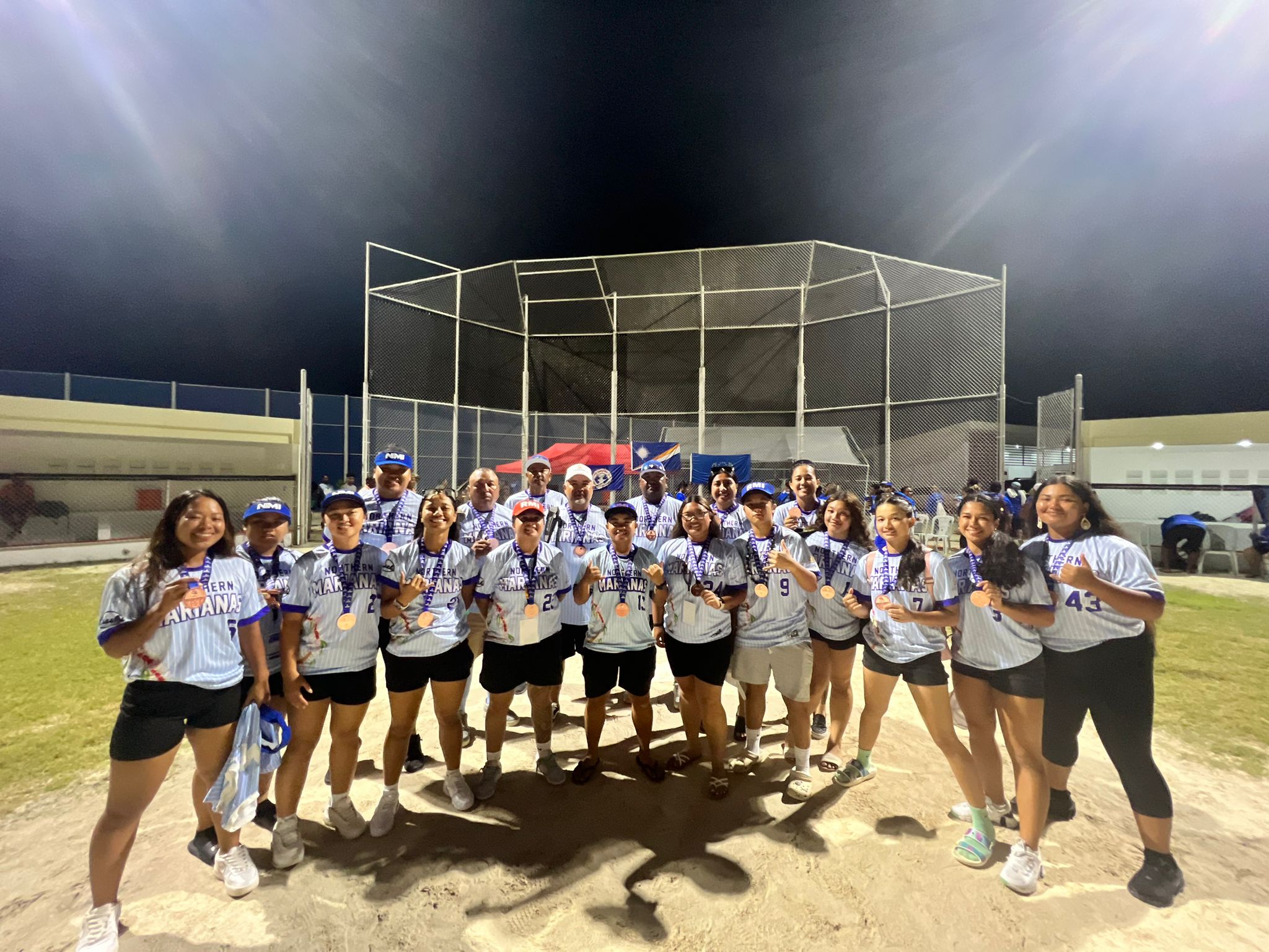 The NMI Women’s Fastpitch Softball players and coaches pose with their bronze medals.