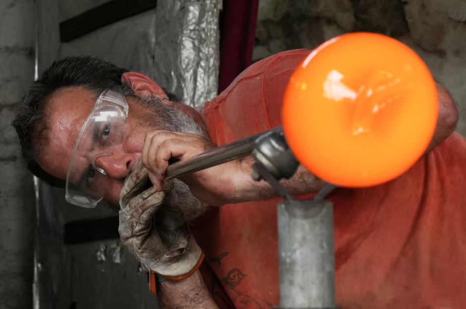 Glassmaker Eduardo Viciana blows molten glass in his atelier in Havana, Cuba, June 21, 2024.