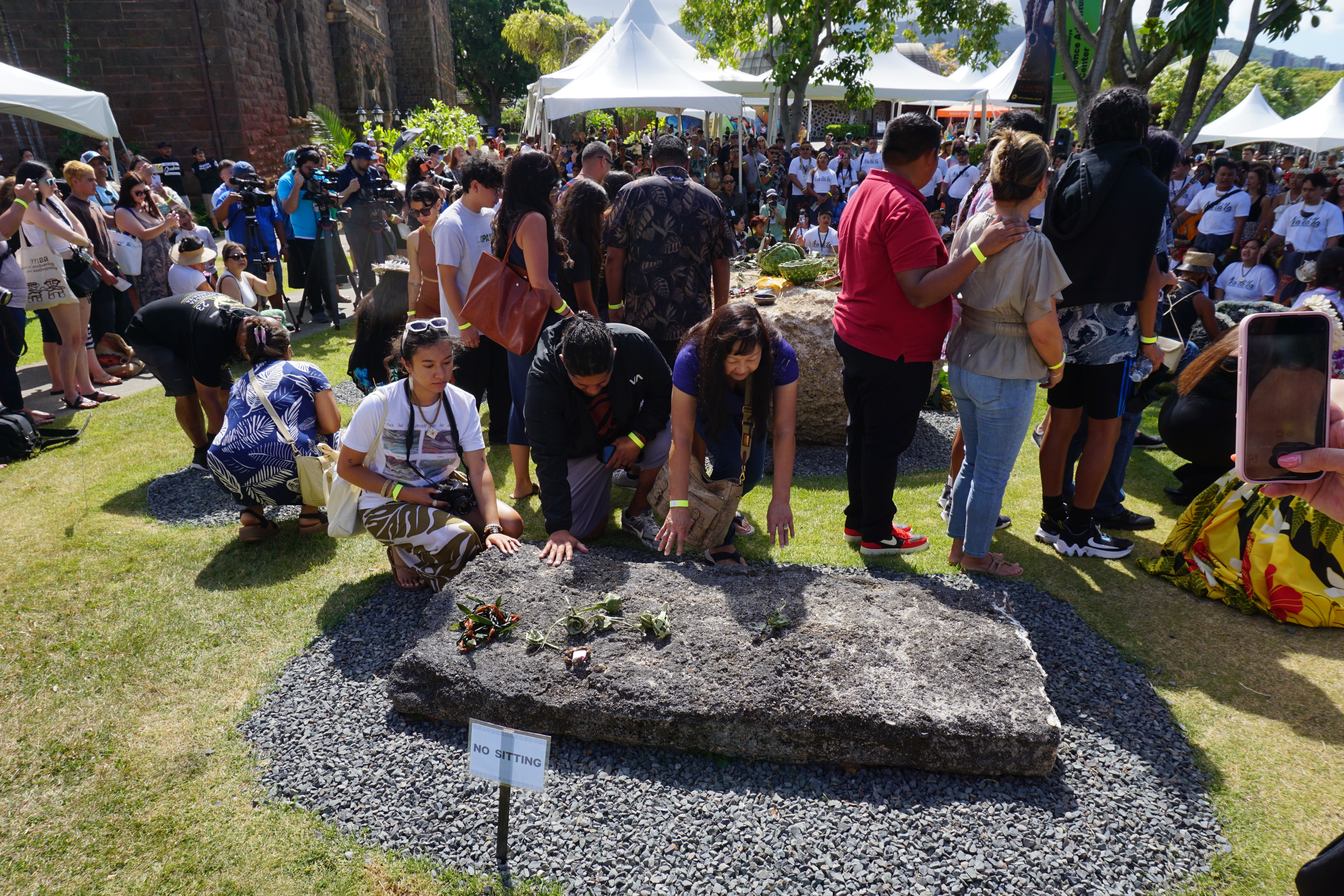 Participants touch the latte stones during the ceremony.