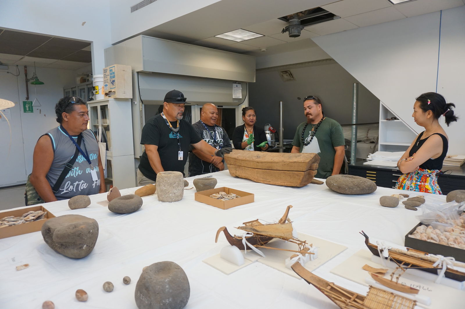 From left, Jason Aldan, Martin Naputi, Jack V. Diaz, Erlinda Naputi, Tyler Warwick, and Sarah Kuaiwa examine a wooden box from Yap that is part of the Hornbostel Collection. Around them are numerous stone artifacts and other items in the collection at the Bishop Museum.
