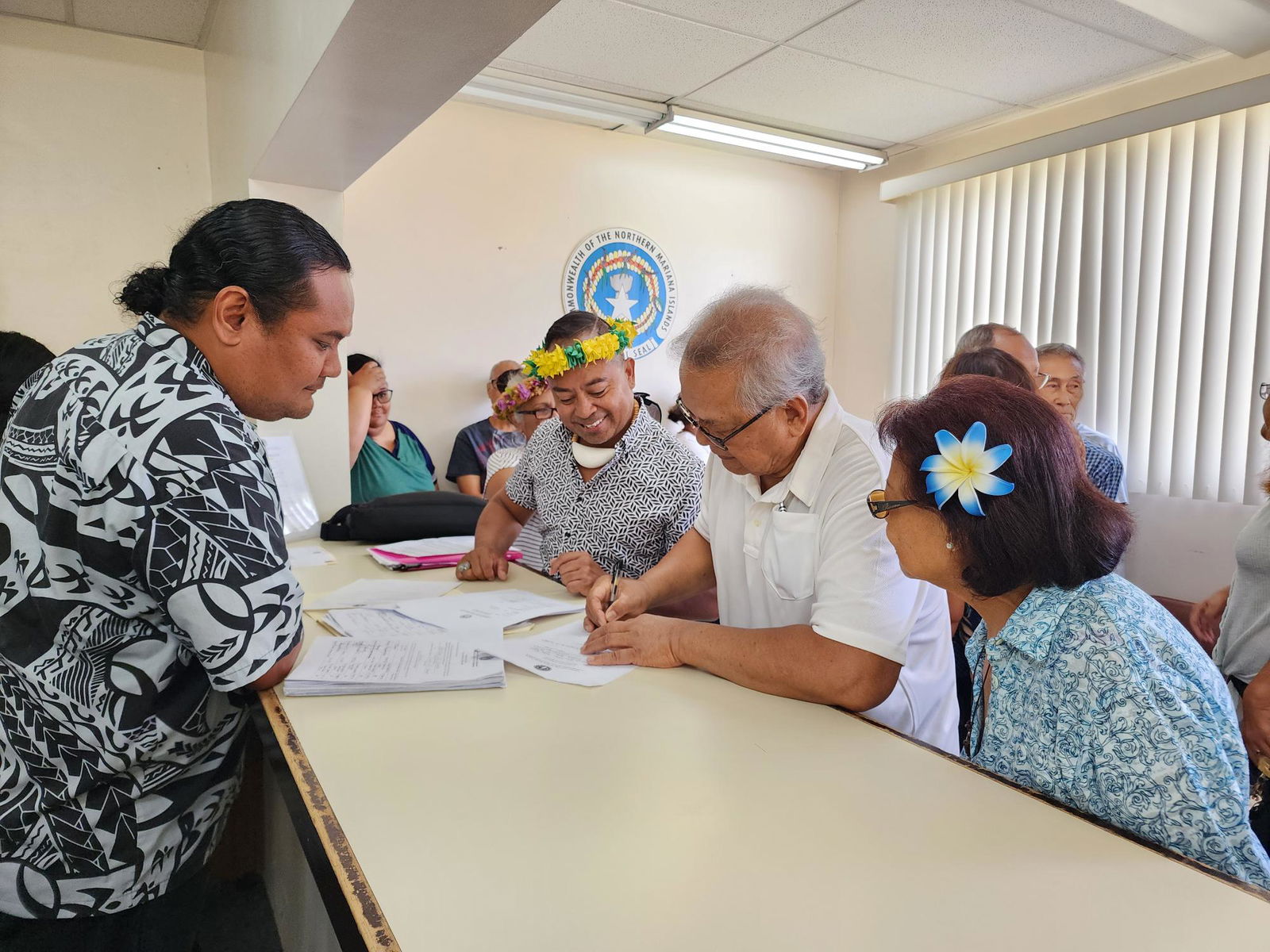 John Oliver Delos Reyes Bolis Gonzales smiles as former Rep. Ray Basa, co-vice chairman of the Committee to Elect Gonzales, signs election commission documents while Ignacia I. Piteg and CEC administrative officer AJ Lisua look on.