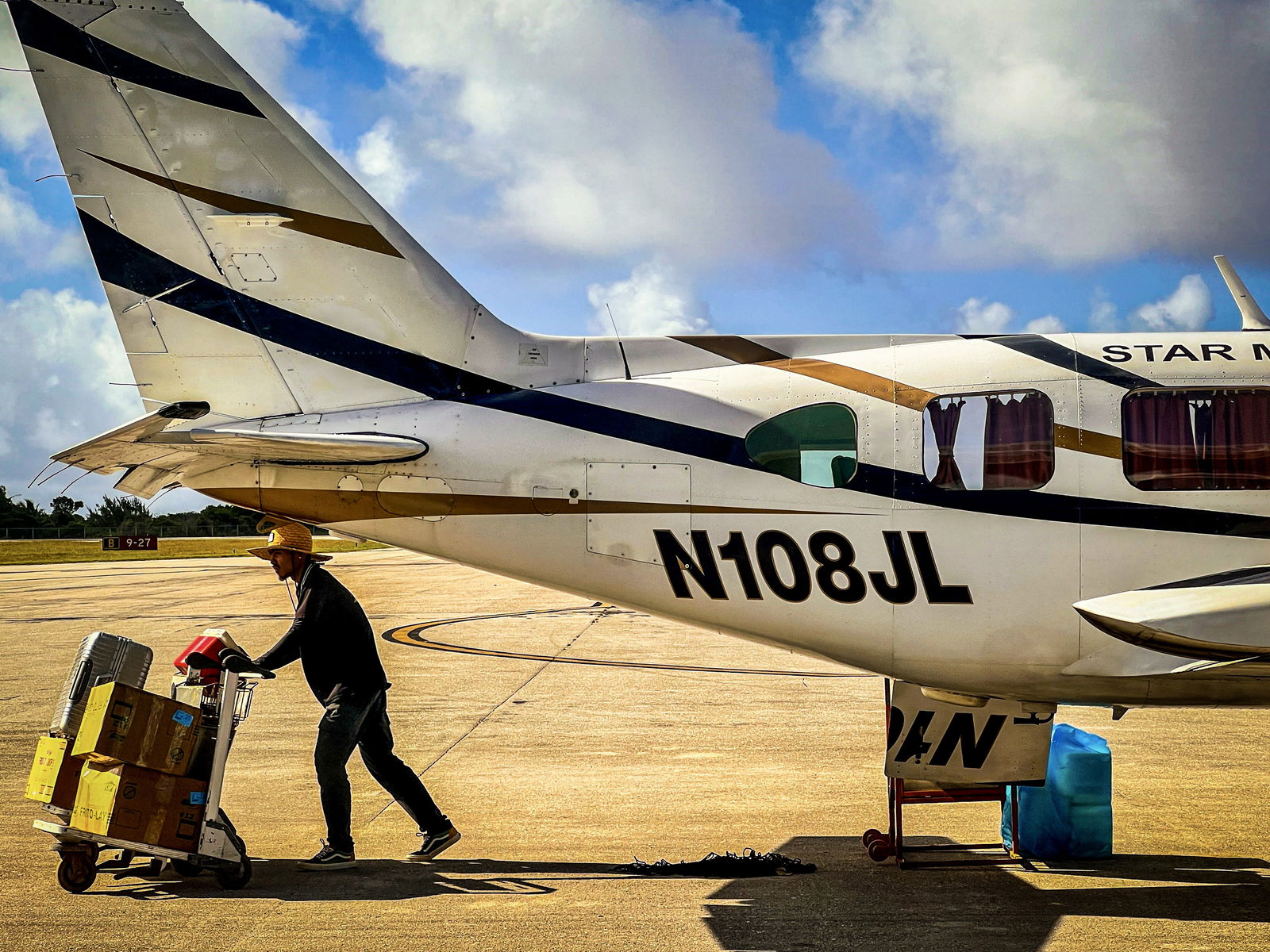 A Star Marianas Air ground crew member pushes a luggage cart near a newly arrived Piper PA 31-350 Navajo Chieftain at the Benjamin Taisacan Manglona/Rota International Airport.