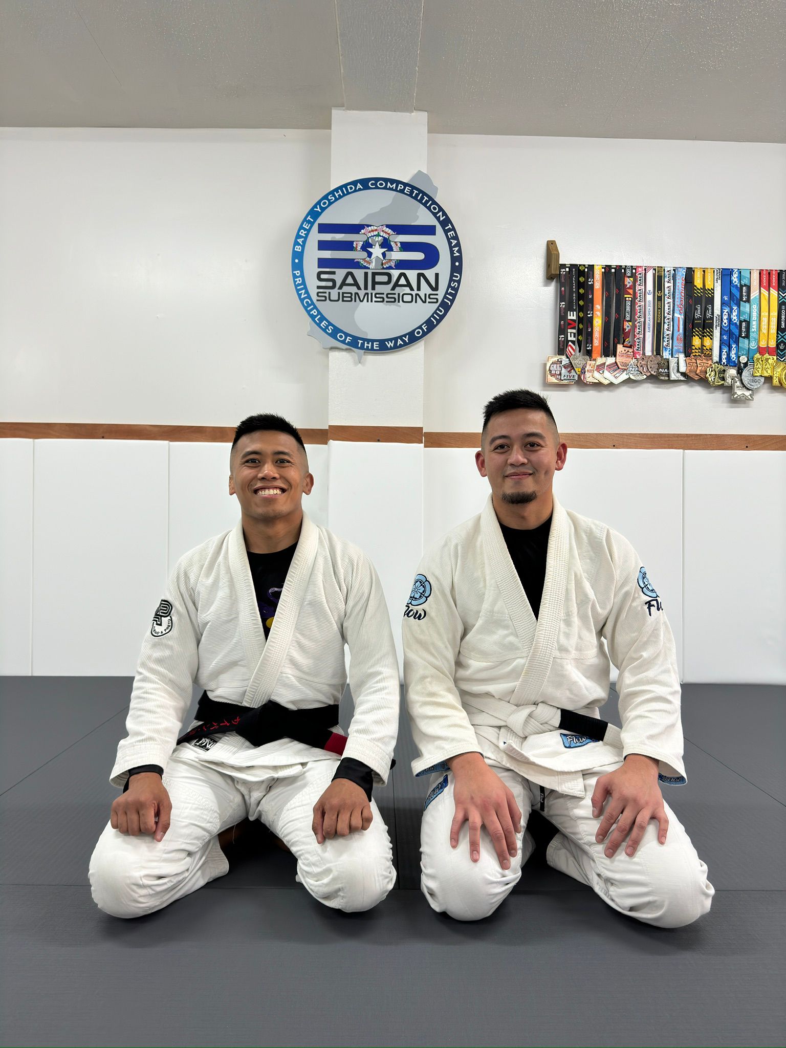 Saipan Submissions teacher and coach Bryan Deleon Guerrero and president Troy Santos pose for a photo during an orientation at their gym at the MSV building in Chalan Kanoa on Saturday.