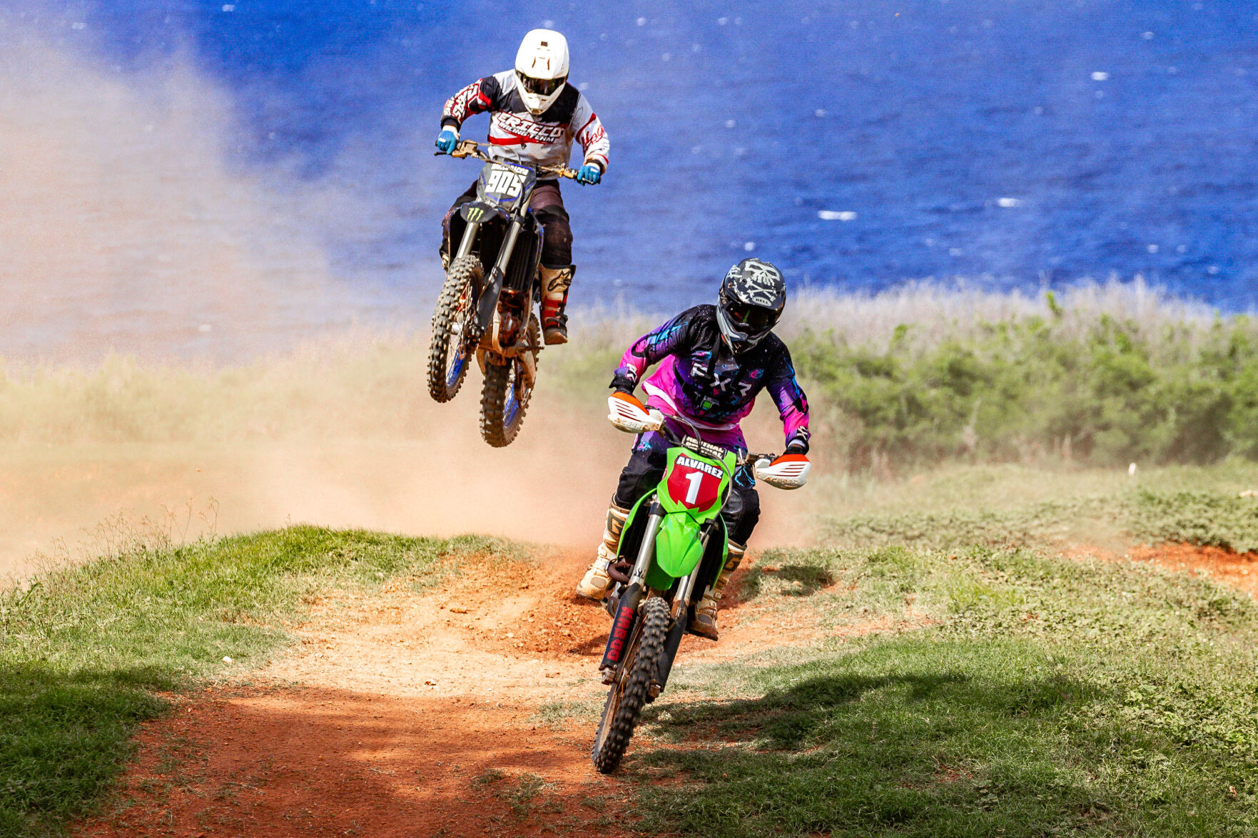 Matthew Guerrero, left, takes to the air as he closes in on Shane Alvarez during a Novice/Expert Class race in round 5 of the MRA Marianas Racing Association “Moto VI” 2024 Points Race Series at the Cowtown Raceway Park on Sunday.