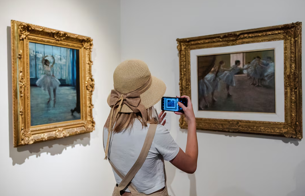 A woman takes a picture of a painting during the "Impressionists instead of heat" campaign, which offers free admission to the Gallery of 19th and 20th Century European and American Art of the State Pushkin Museum in the hottest daytime hours, in Moscow, Russia July 17, 2024.