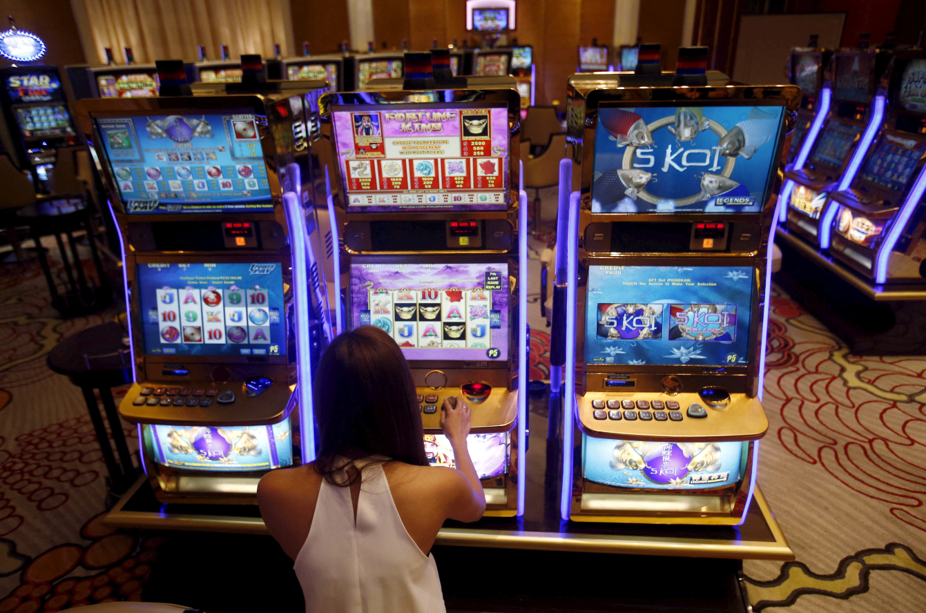 A casino trainee demonstrates how to play a slot machine in the Philippines, April 16, 2015.