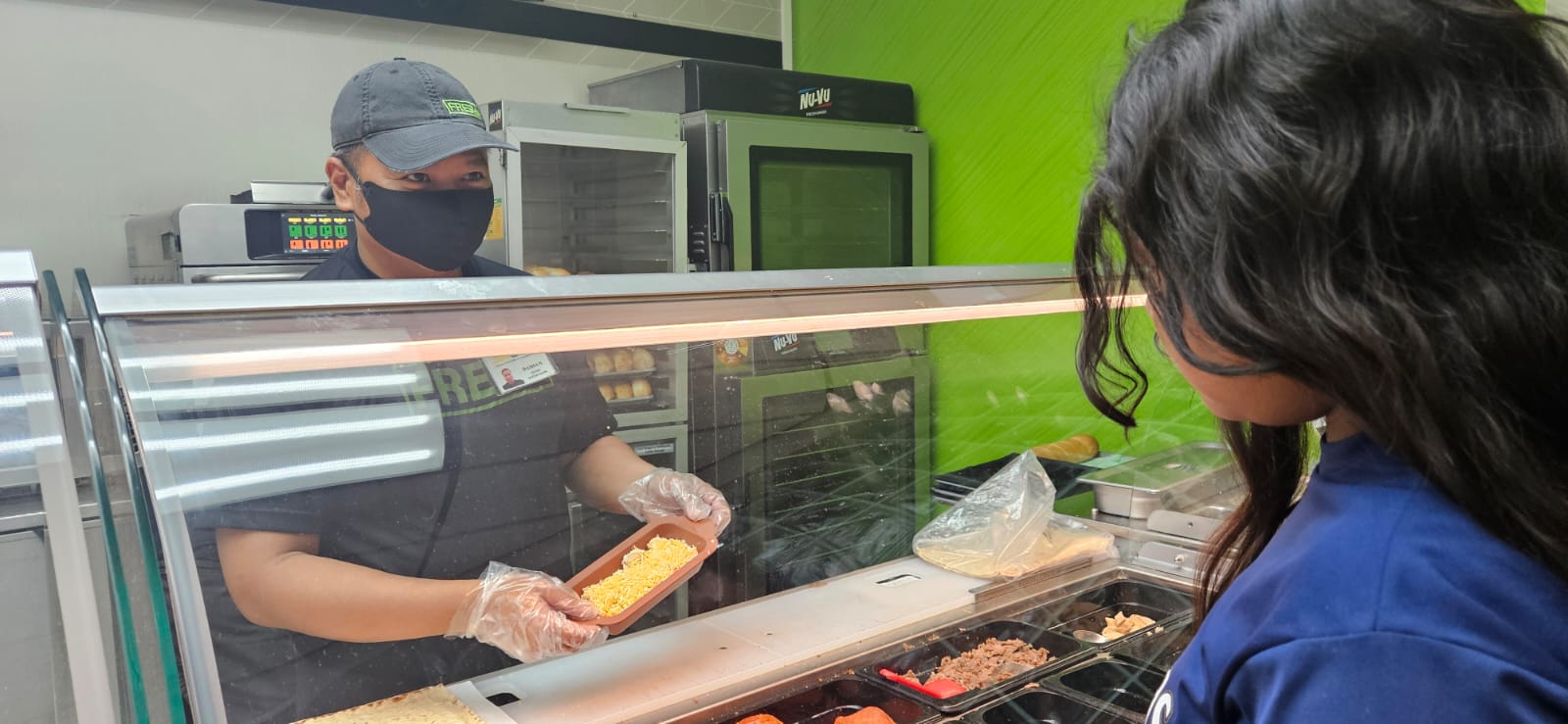 Damian Lastimado Jr. shows a customer what can be added to the Subway Wrap.