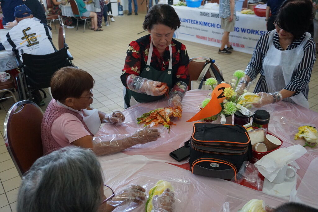 A presenter shows how to rub seasoning into the cabbage to make kimchi.