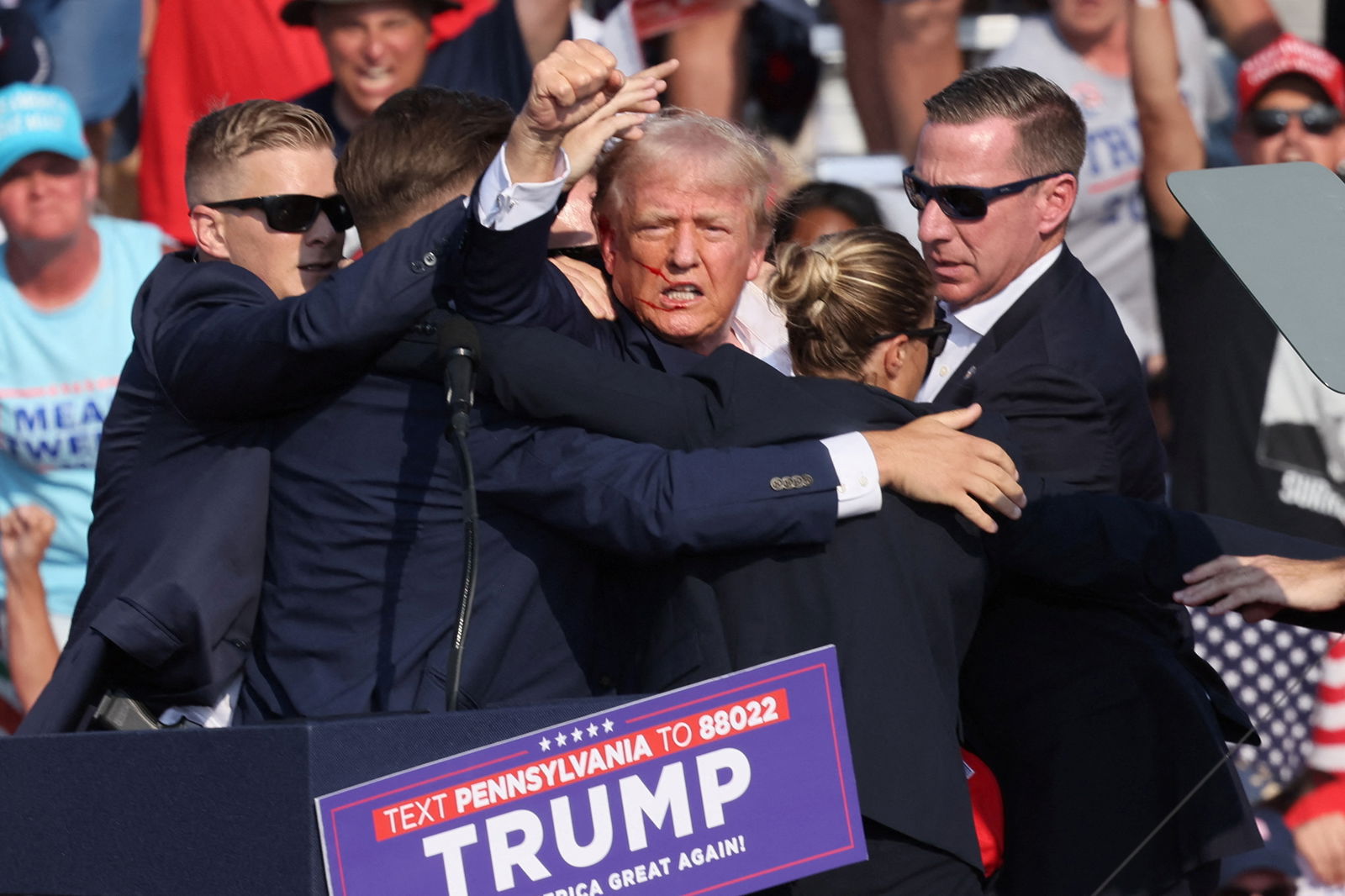 Republican presidential candidate Donald Trump is assisted by security personnel after gunfire rang out during a campaign rally at the Butler Farm Show in Butler, Pennsylvania, July 13, 2024.