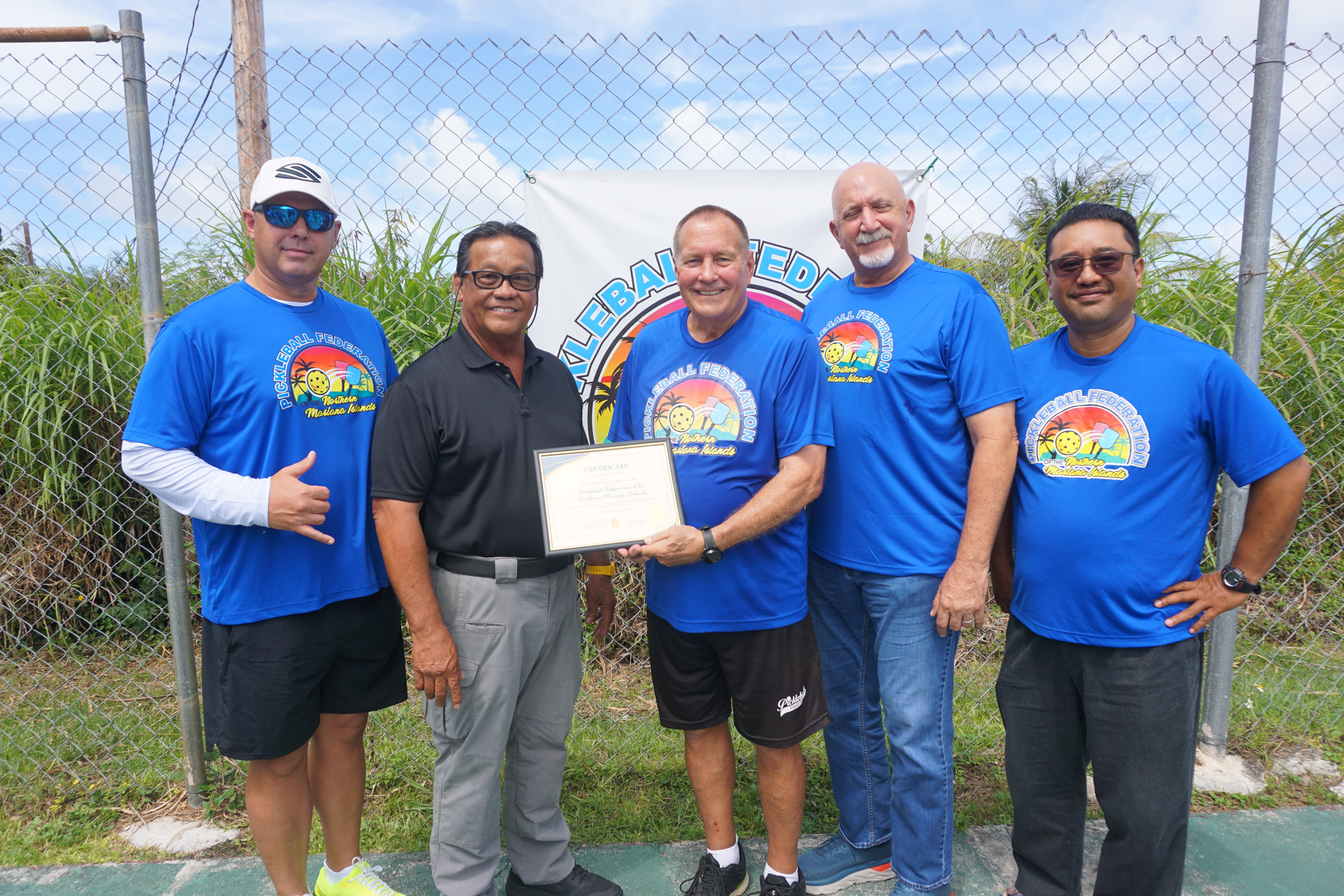 While holding an Adopt-A-Place certificate, Pickleball Federation of the NMI President Nelson Krum, center, poses for a photo with Saipan Mayor Ramon "RB" Camacho, Triple J General Manager Sean Ficke, and federation members Bart Jackson and Dave Guerrero at the Capital Hill tennis court on Friday.