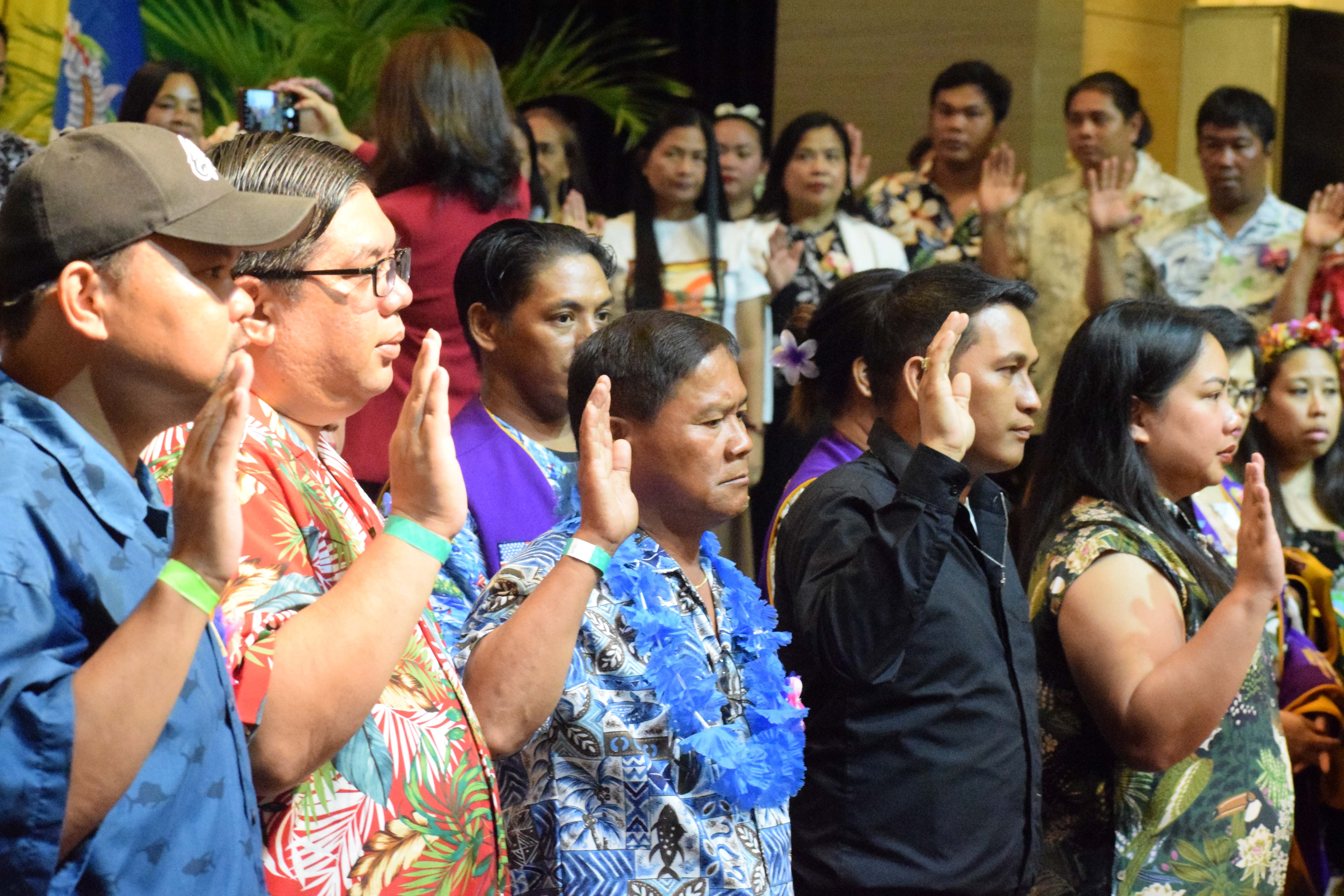 The new members of the six clubs of Lions Clubs International's District 204 raise their right hands during an induction ceremony at the Saipan World Resort's Royal Taga Hall on Saturday.