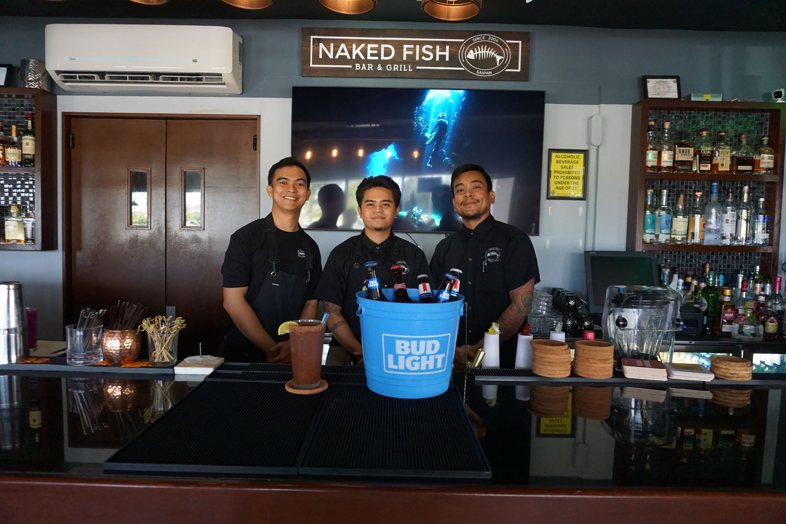 From left, Nikko Guerrero, JP Isip, and Jeff Mendoza pose for a shot with the michelada and bucket of buds at Naked Fish​.