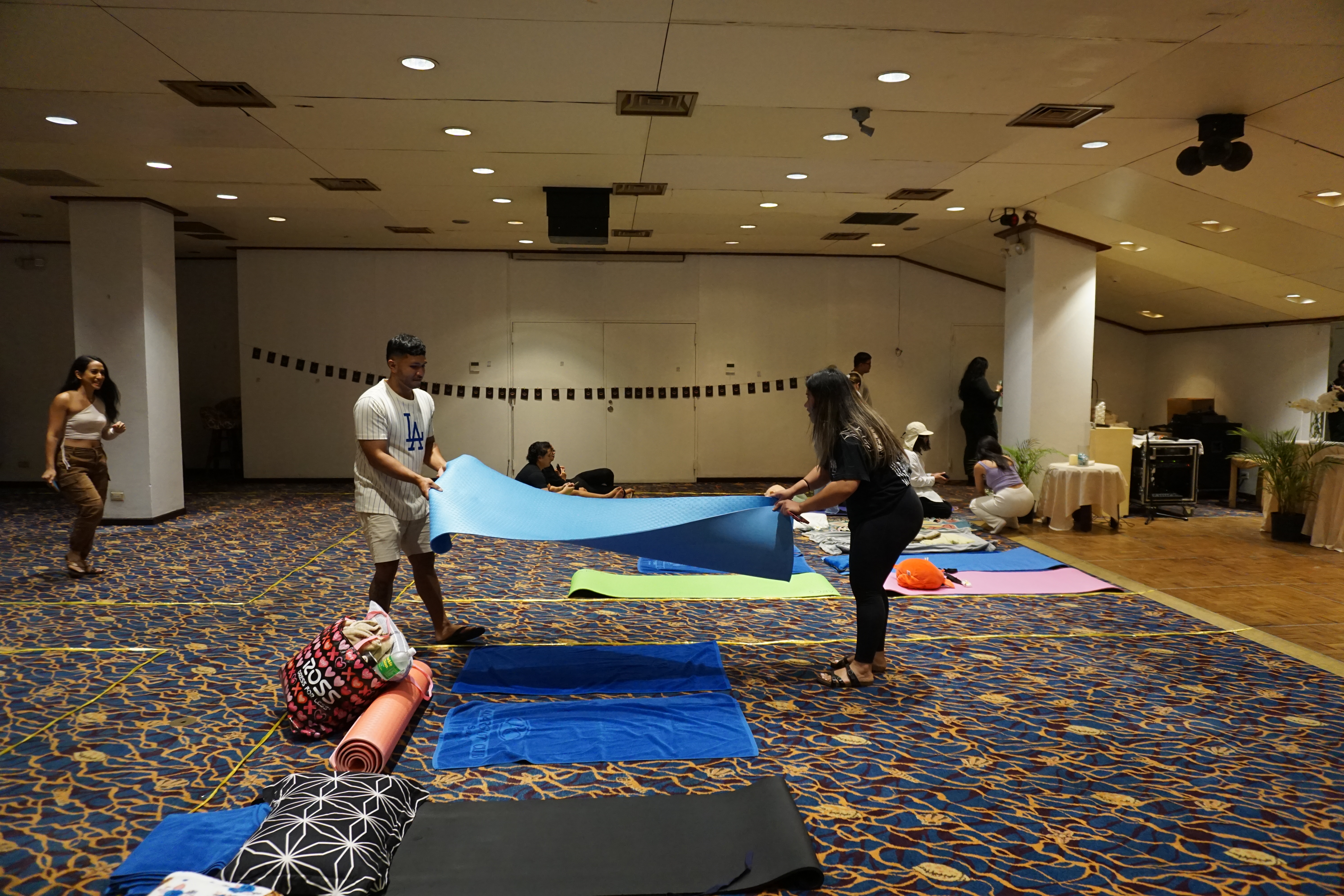 Two participants prepare a yoga mat prior to the start of the sound bath.