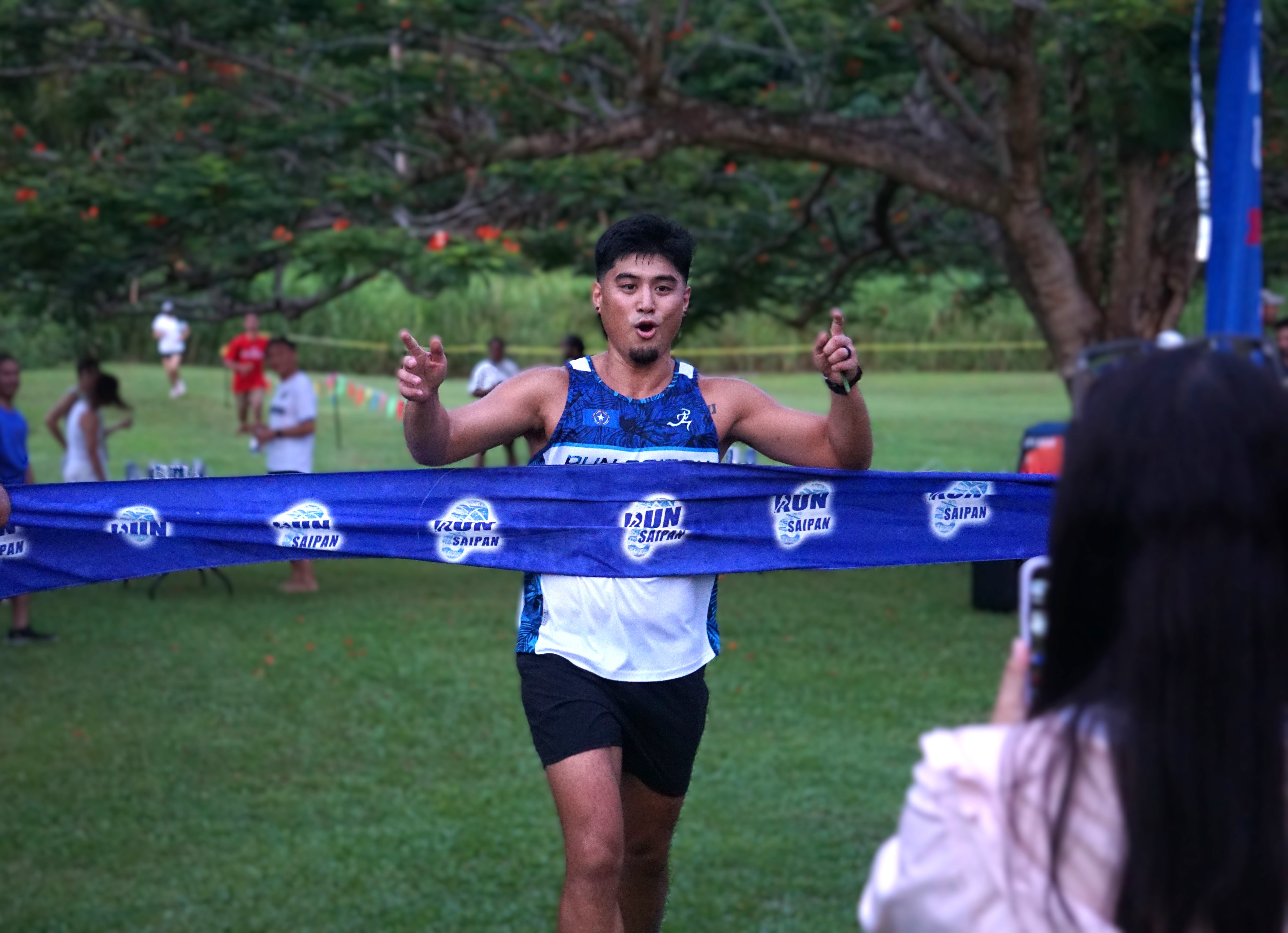 The Clique's Aaron Pamintuan smiles as he crosses the finish line in the corporate relay division of the 3rd Annual Michelob Ultra Beer Mile 2024 at the Saipan Vegas Country Club on Friday.