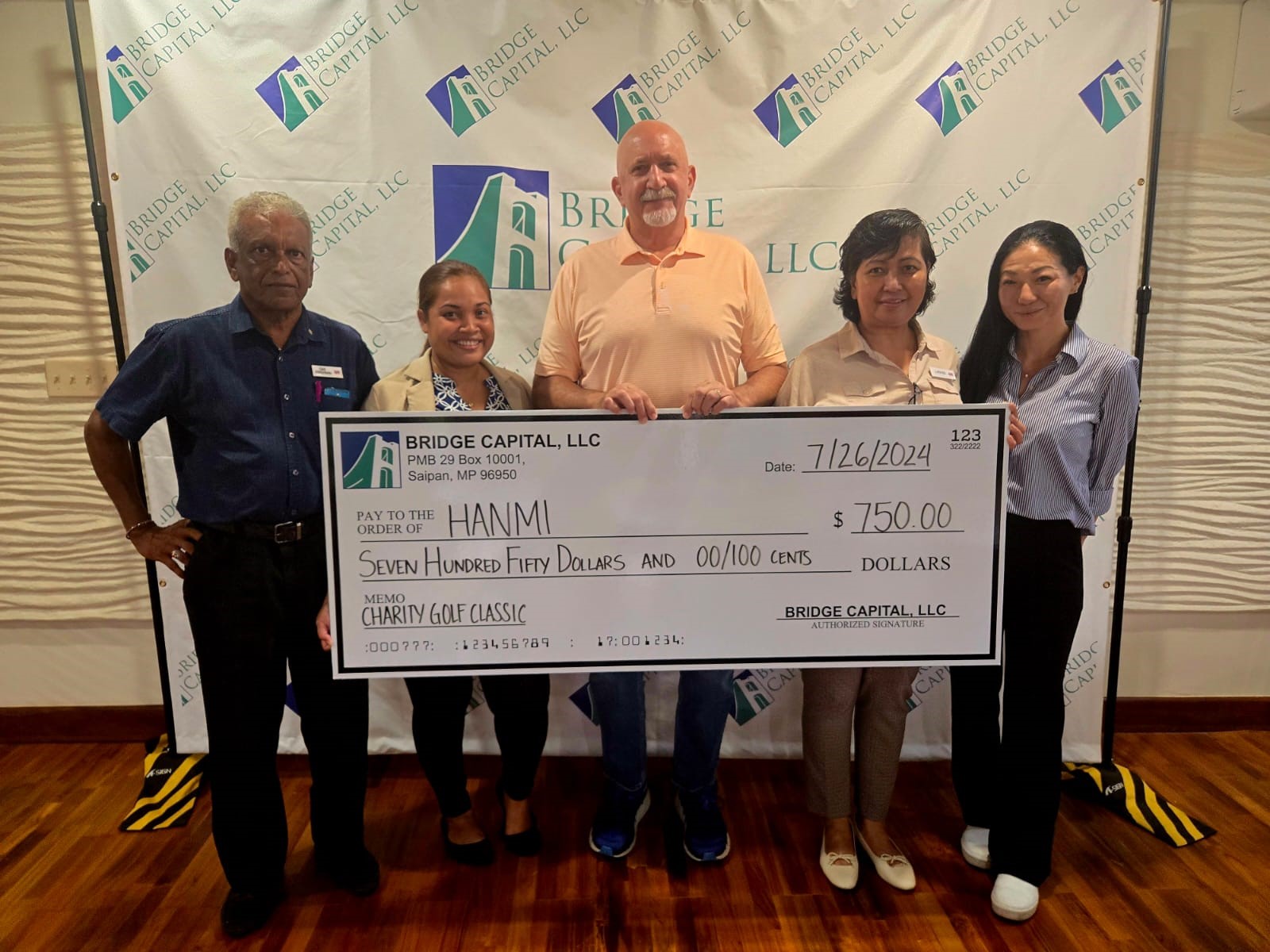 Bridge Capital LLC Vice President/GM Bartley Jackson, center, presents $750 cash on July 26, 2026, for the 22nd Annual HANMI Charity Classic Golf Tournament.  Bridge Capital is a Superior Package sponsor for the tournament, slated for Aug. 24, 2024, at Coral Ocean Resort.  From left, Tournament Chairman Das Krishnan, tournament committee member Julie Litulumar, Jackson, and tournament committee members Loida Sabanal and Victoria Lee.