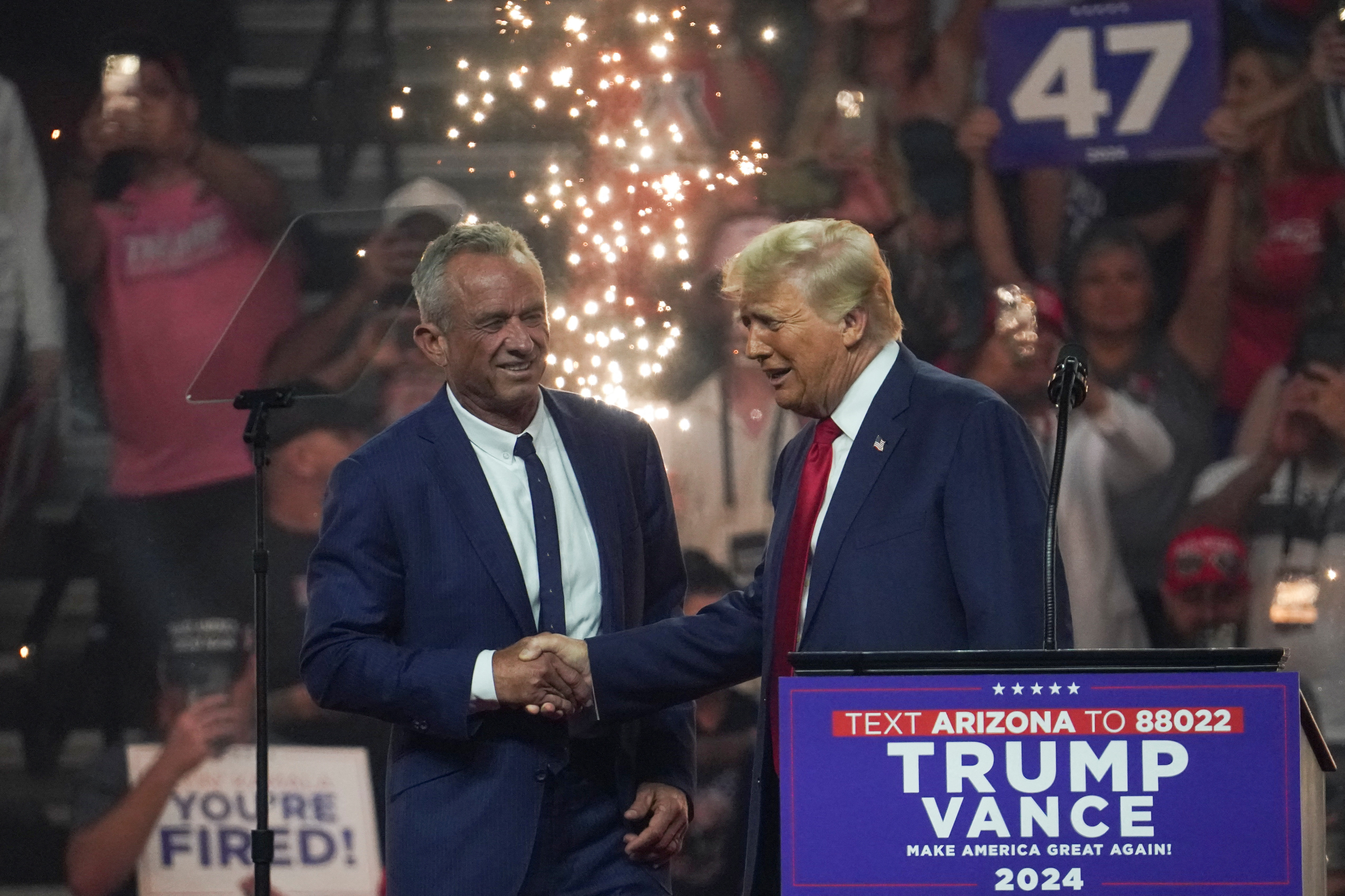 Republican presidential nominee Donald Trump shakes hands with former independent presidential candidate Robert F. Kennedy Jr. during a rally in Glendale, Arizona, Aug. 23, 2024.