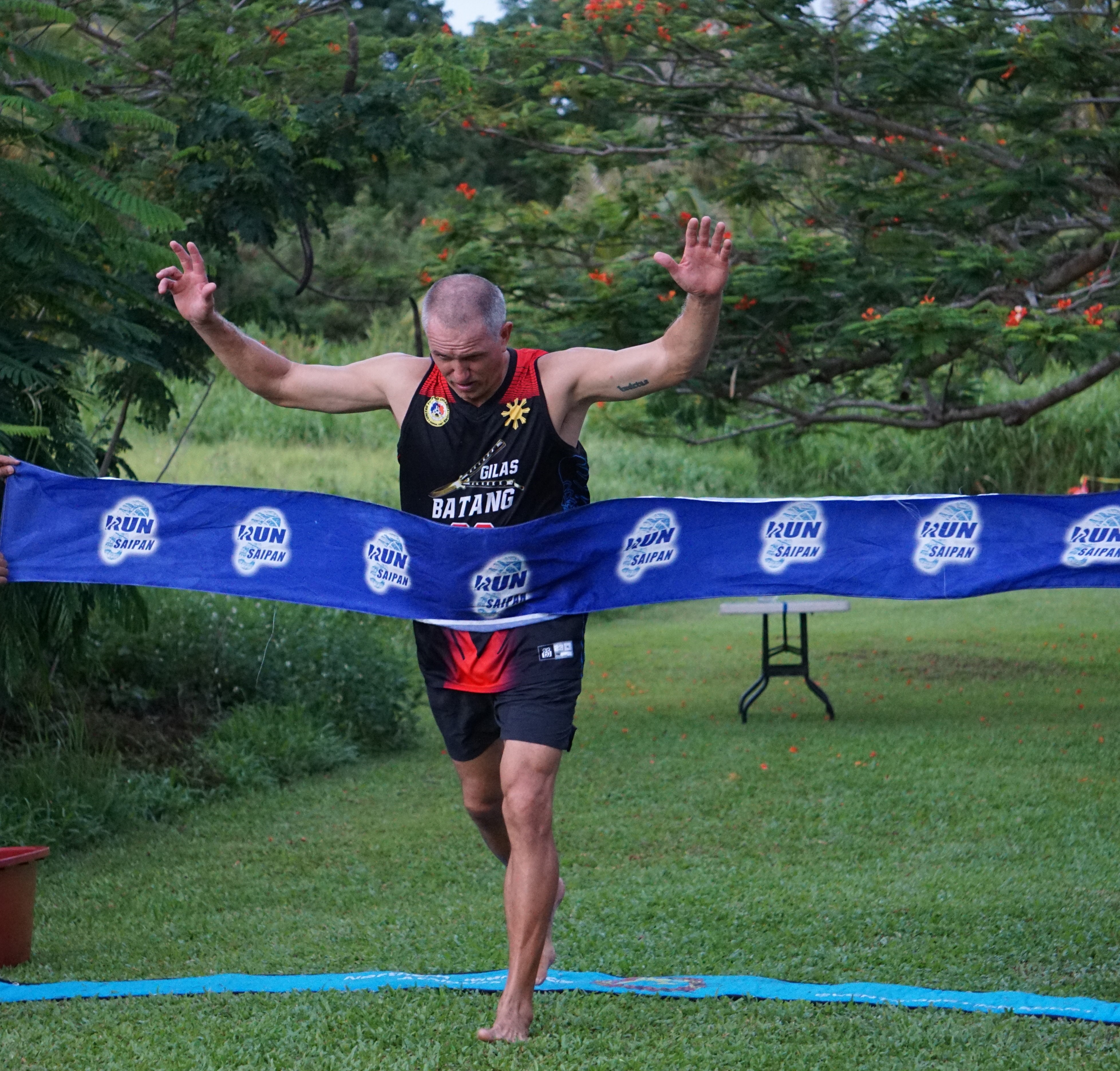 Leith Poole raises his hands as he tops the men's division of the 3rd Annual Michelob Ultra Beer Mile 2024 at the Saipan Vegas Country Club on Friday.
