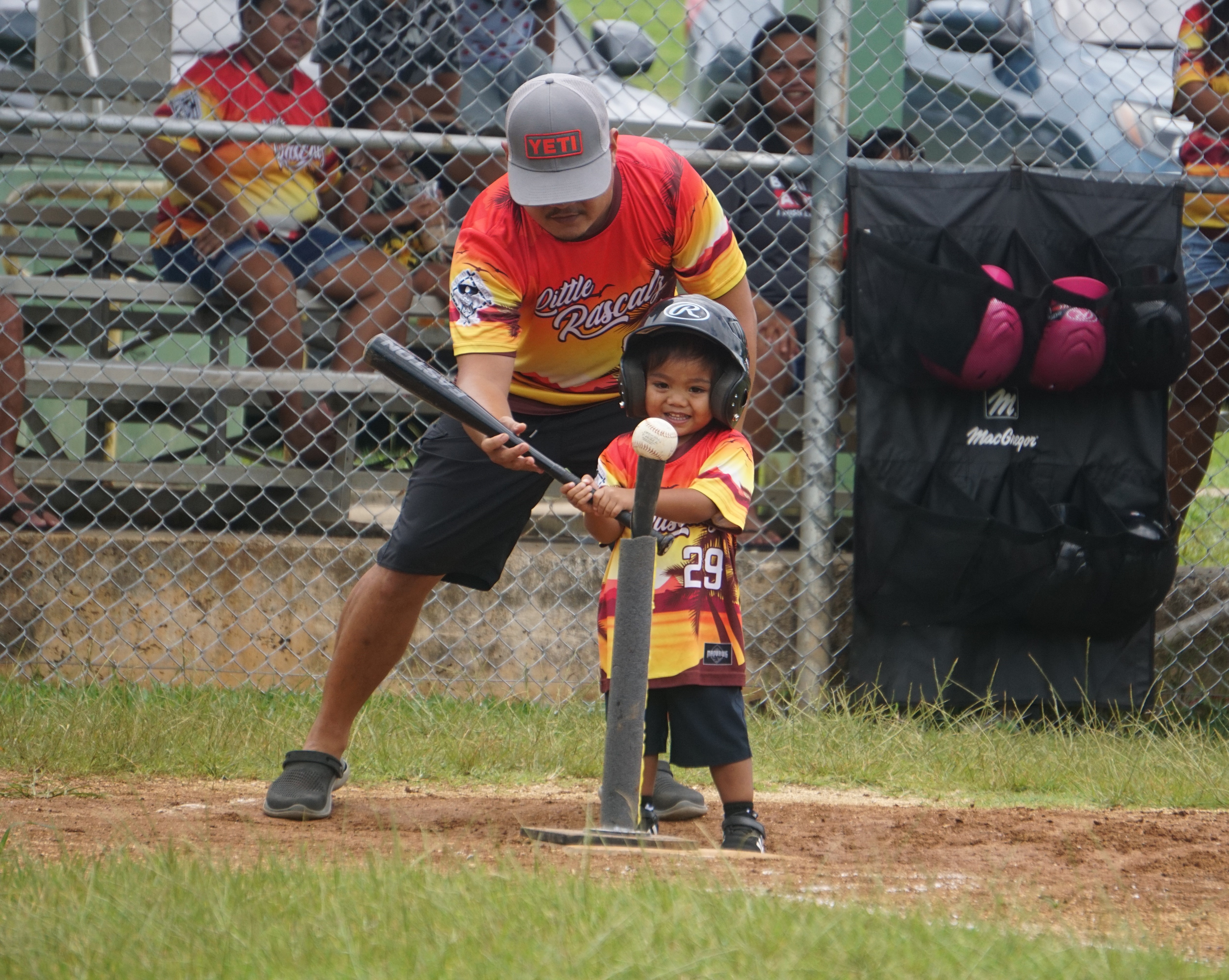 A parent guides a Little Rascal player during his turn at bat in a game against the Little Zogai in the 2024 Natibu Sports Association “Cover Home” Tee-Ball Summer League at the Capital Hill softball field on Saturday.