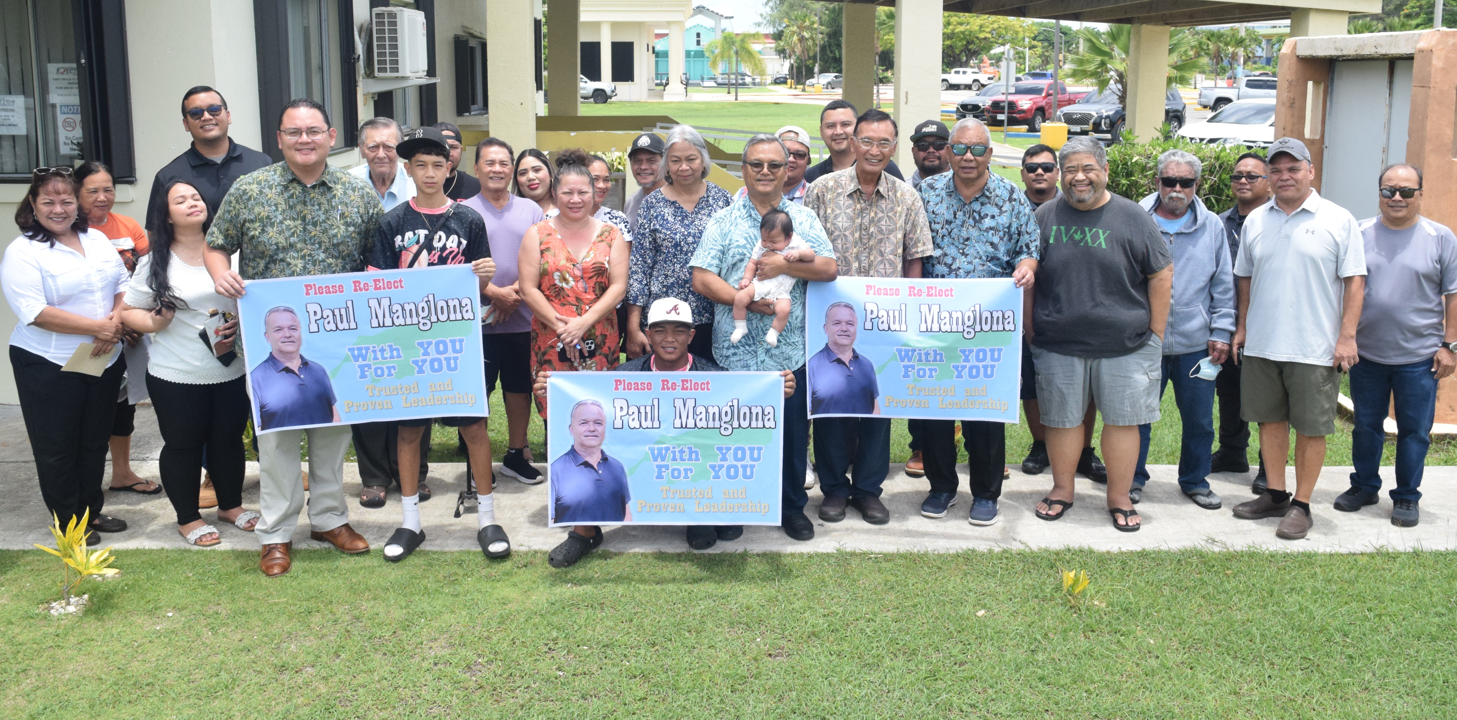 Sen. Paul A. Manglona, center, holding a baby, poses for a photo with family, friends and other supporters at the Commonwealth Election Commission.