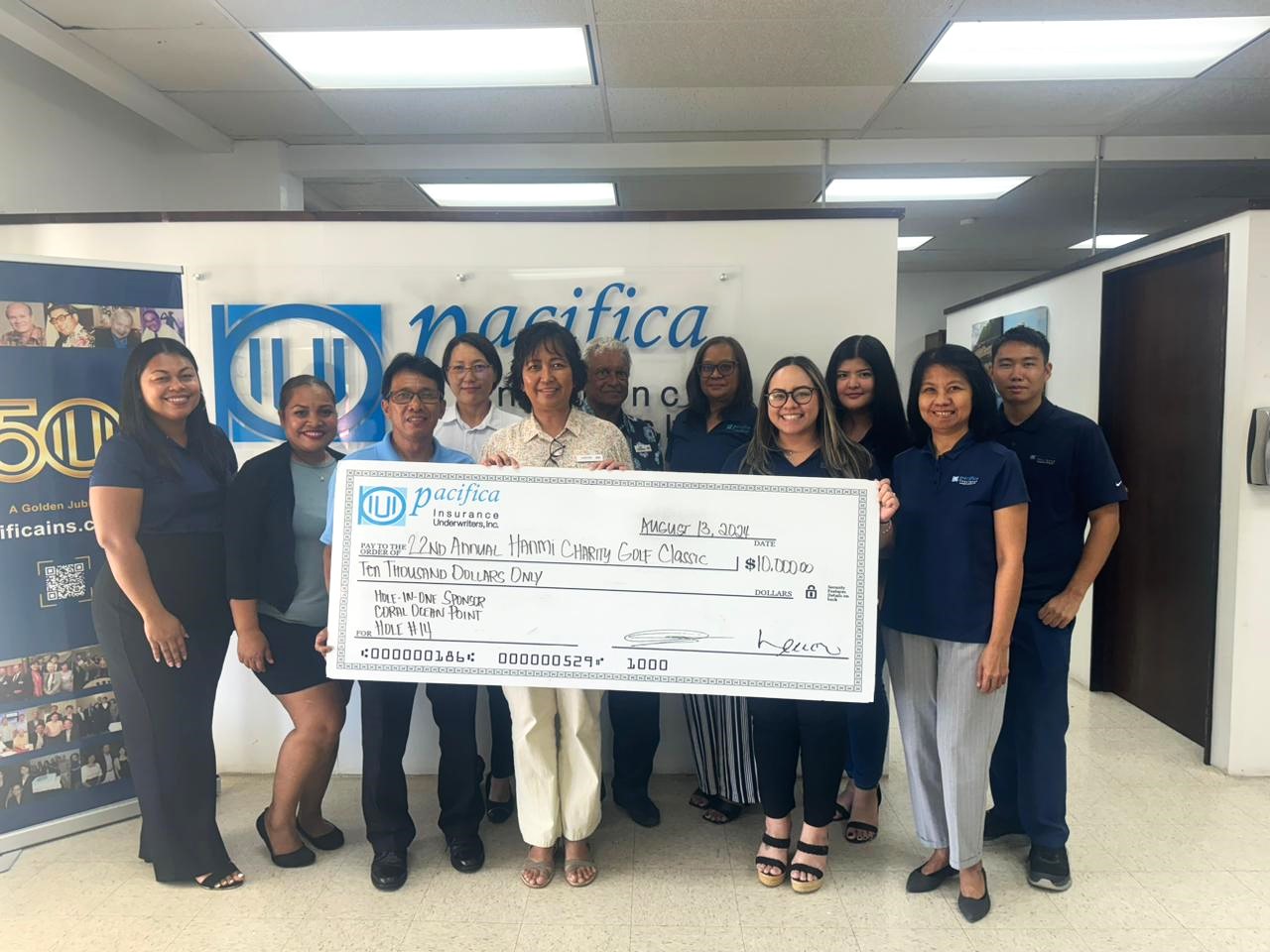 Pacifica Insurance President Shirley Sablan donates a $10,000 hole-in-one prize on Aug.13, 2024, at the branch office in Susupe, Saipan, for the 22nd Annual HANMI Charity Classic Golf Tournament.  The tournament will be held on August 24, 2024, at Coral Ocean Resort Saipan.  Also pictured are other Pacific Insurance management and staff and members of the golf tournament committee.