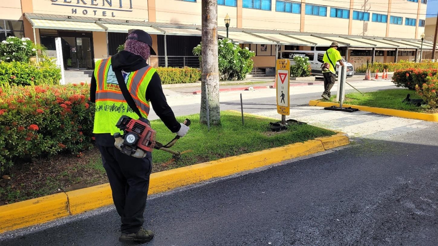 Dennis Reyes, left, of LJ’s Lawncare Service and Jeffrey David help spruce up Beach Road in Garapan on Aug. 14, 2024.  The Marianas Visitors Authority, which contracts the company, is encouraging area tenants to help revitalize the area by cleaning and sprucing up the areas in front of their businesses.
