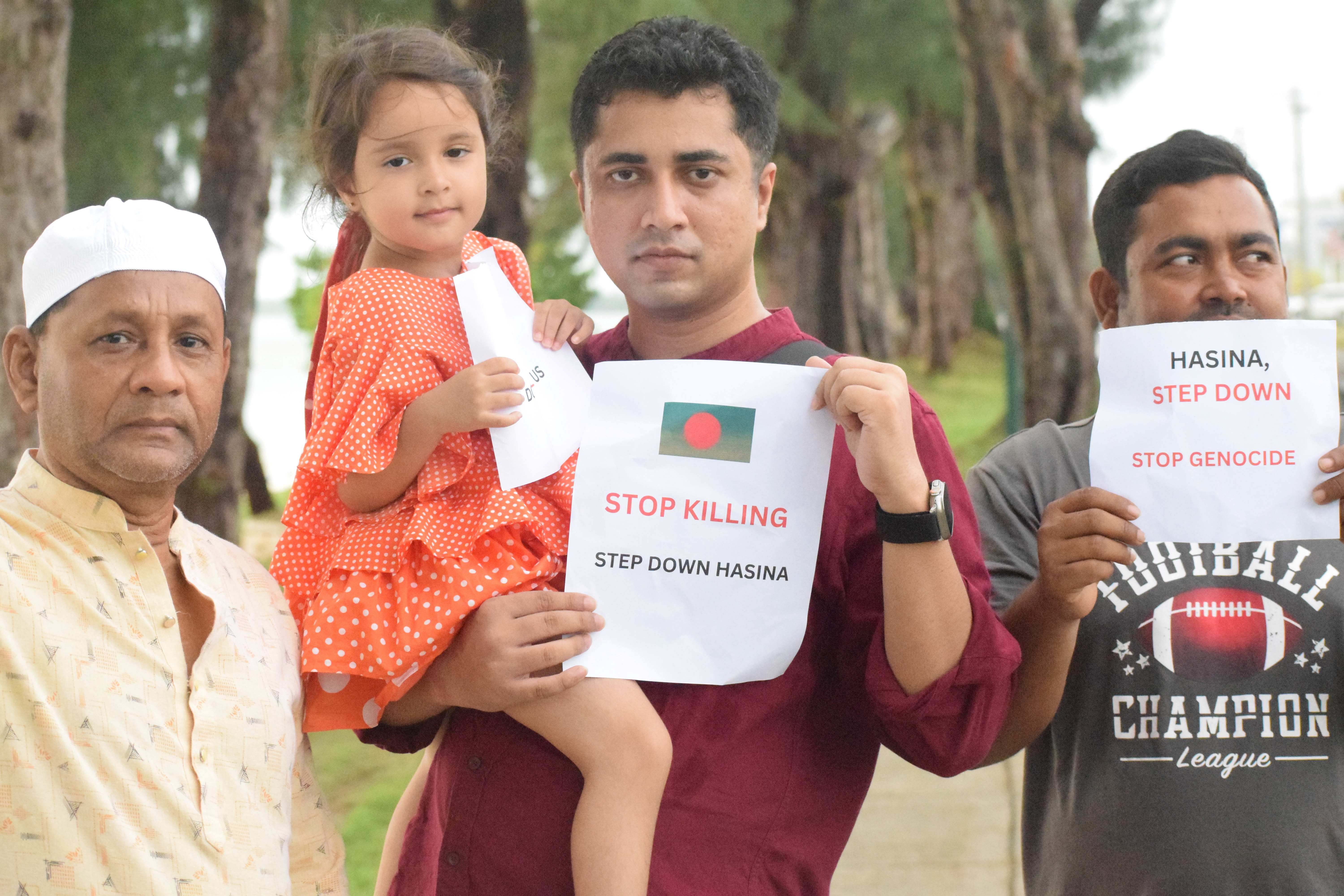 Tareq Jobayere carries his daughter as he poses with two other protesters.