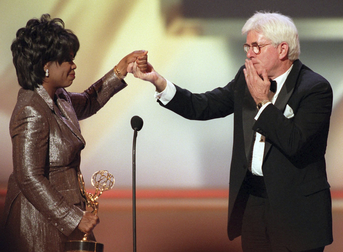 Phil Donahue blows a kiss to Oprah Winfrey as she presents him with a Lifetime Achievement Award at the 23rd Annual Daytime Emmy in New York on May 22, 1996.