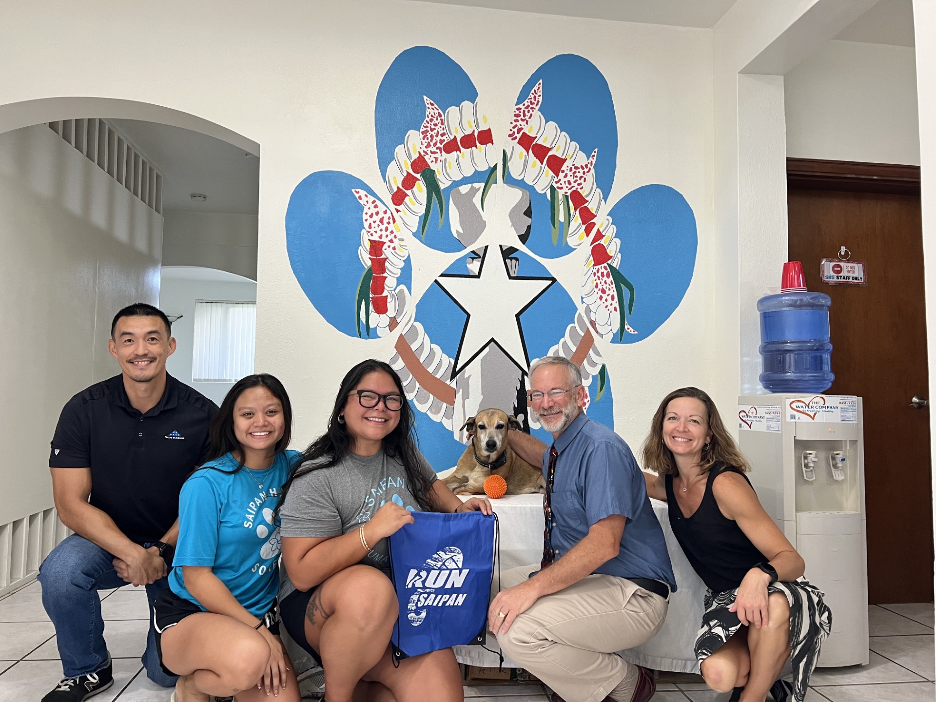 Ron Snyder from Run Saipan and James Lee and Heather Popa, representing Michelob Ultra present a Run Saipan Bag and a check to the Saipan Humane Society and their resident dog, Grandma.