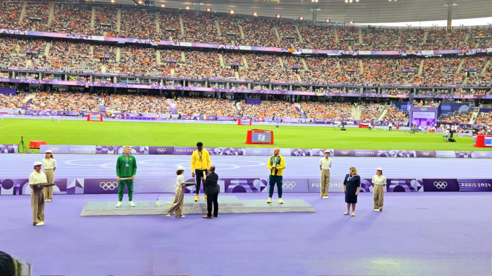 The NMI’s Robin Sapong, front row, 2nd left, hands a gift during the medal presentation in the men’s discus throw event.