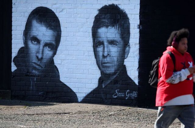 A man walks past a mural of Oasis band members Liam and Noel Gallagher by artist Snow Graffiti on the wall of the Coach and Horses pub in Whitefield, near Manchester, Britain, Aug. 31, 2024.
